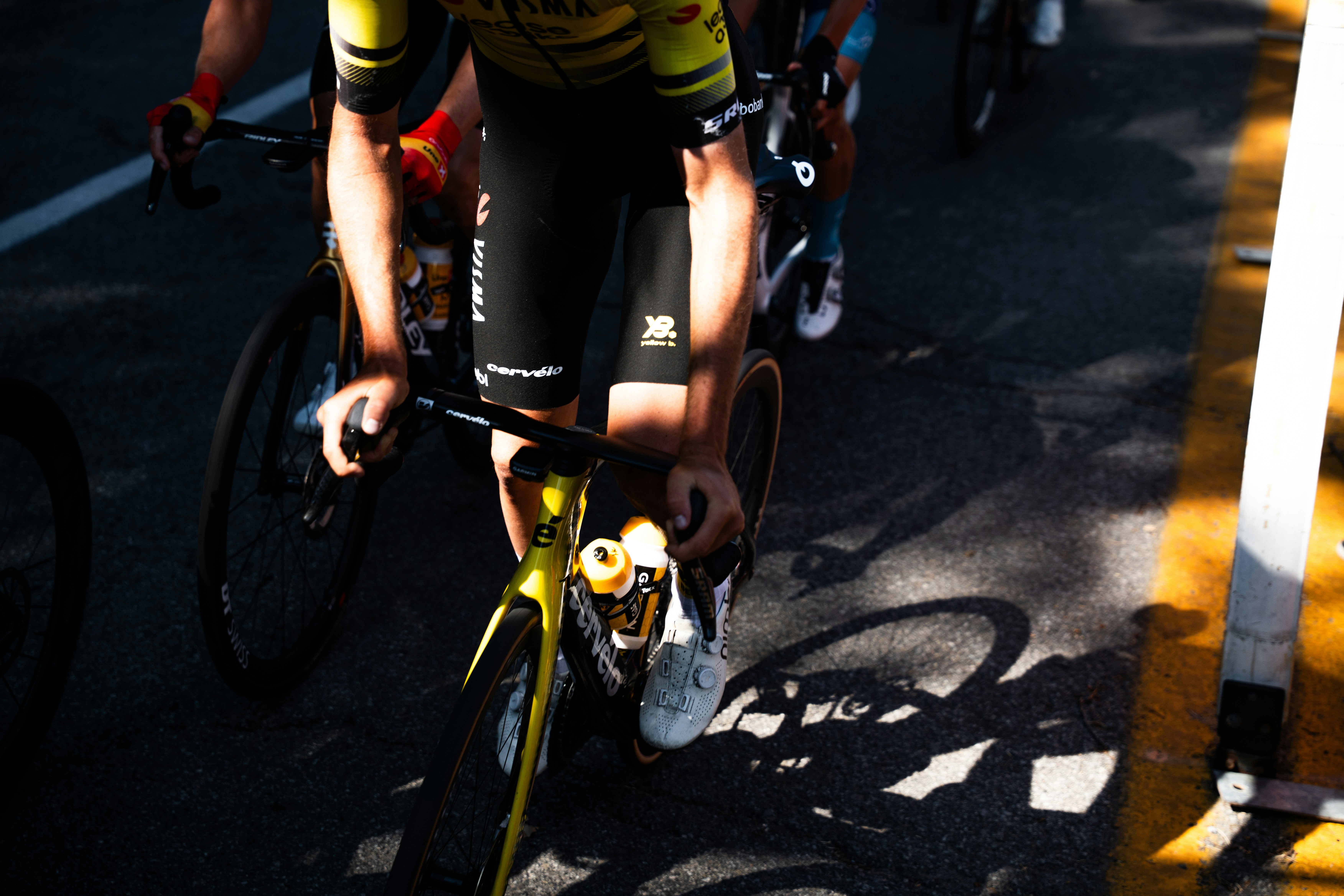 Cyclists racing on a sunny road with shadows