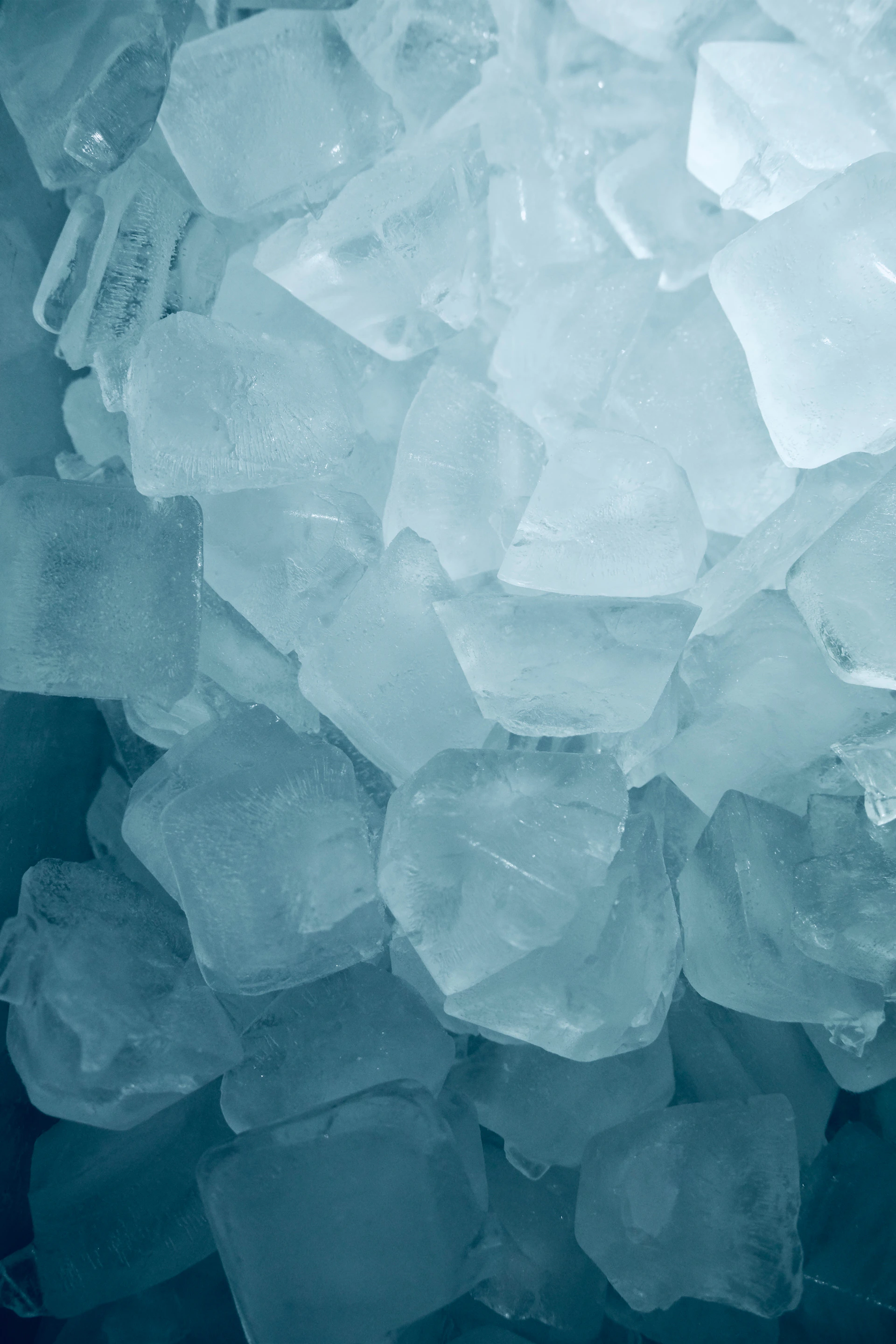 A pile of clear ice cubes with blue tint