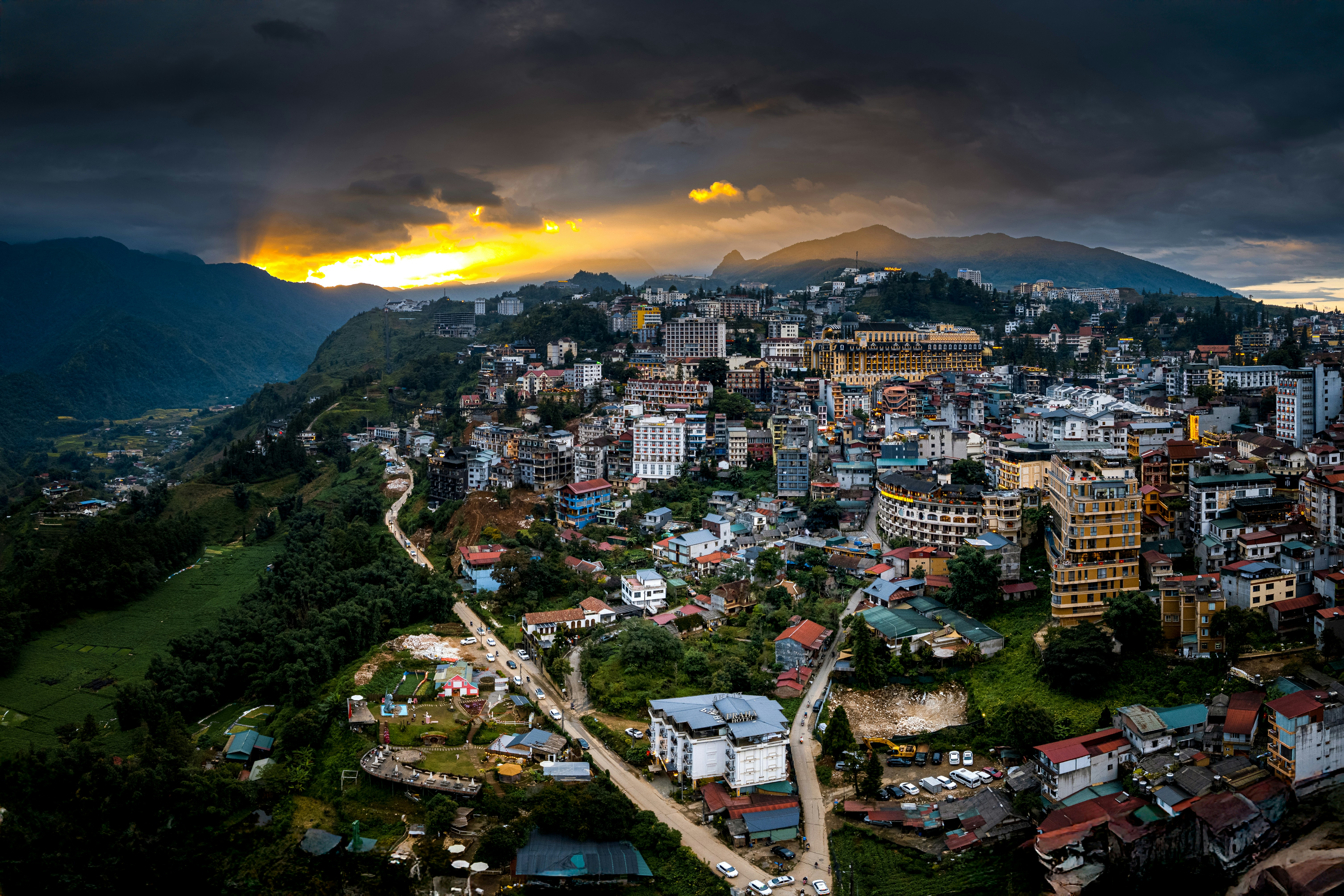 Cityscape nestled in mountains during a dramatic sunset.