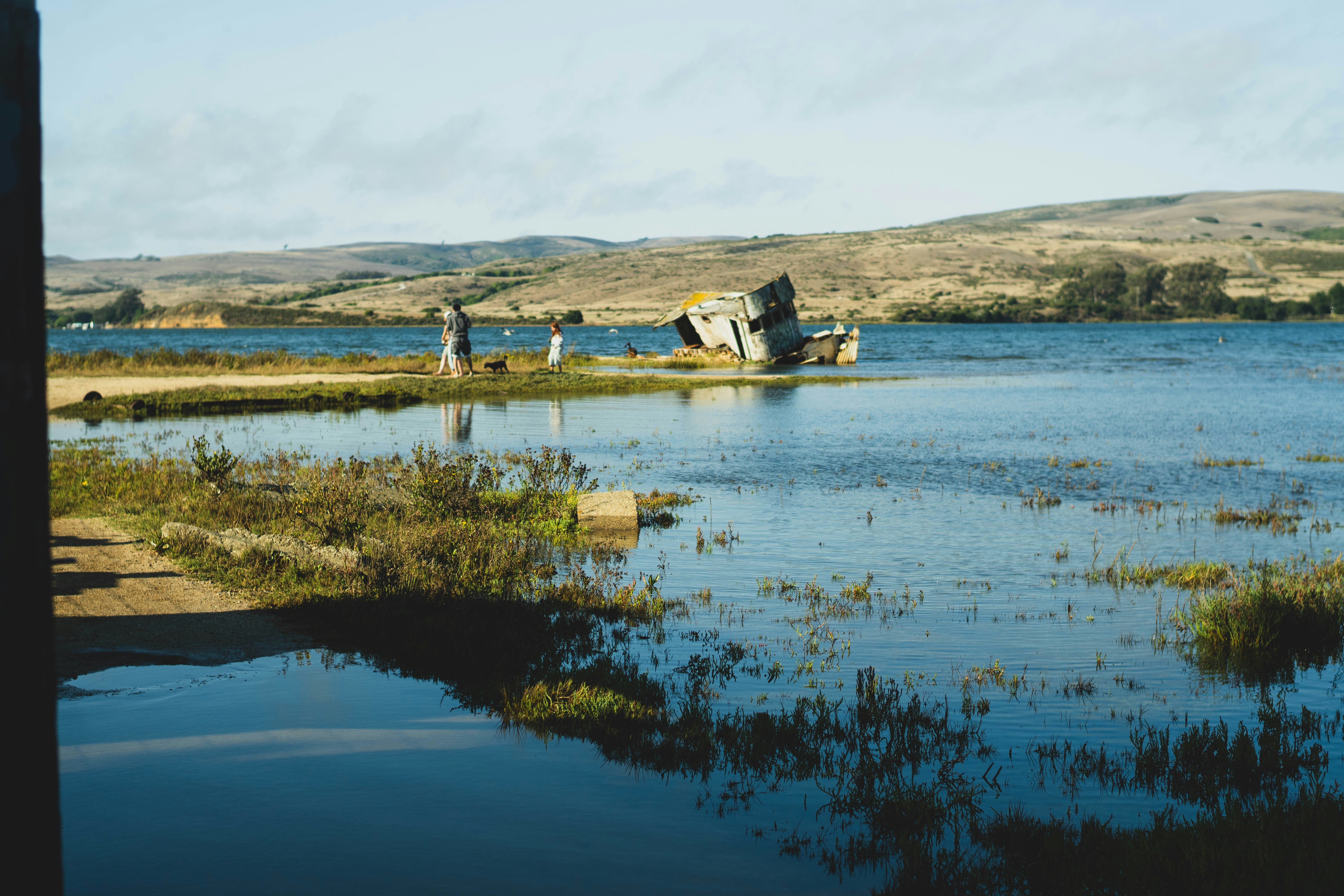 People standing by a rocky shore with calm water.