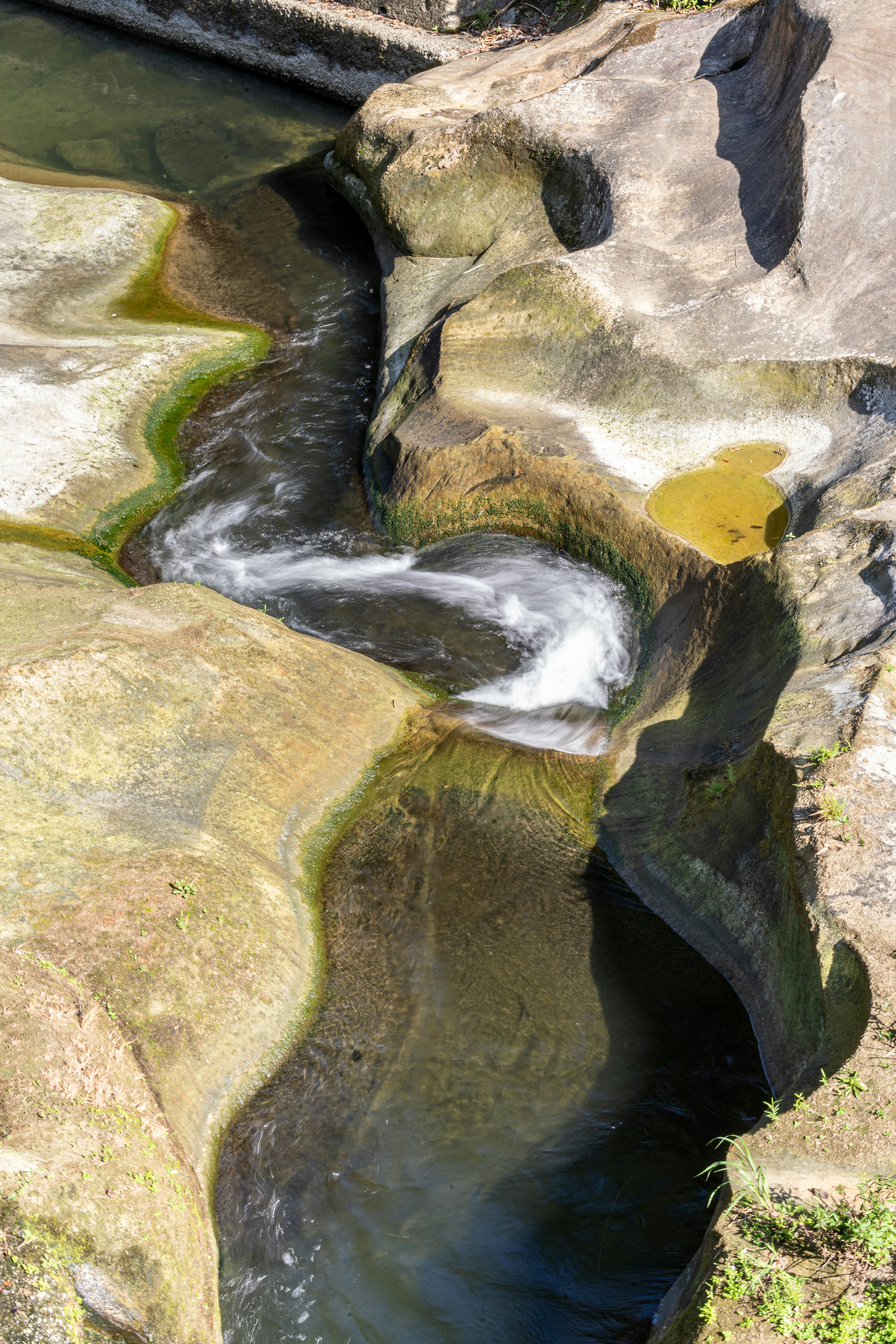 Water flows through carved rock formations in a natural setting.