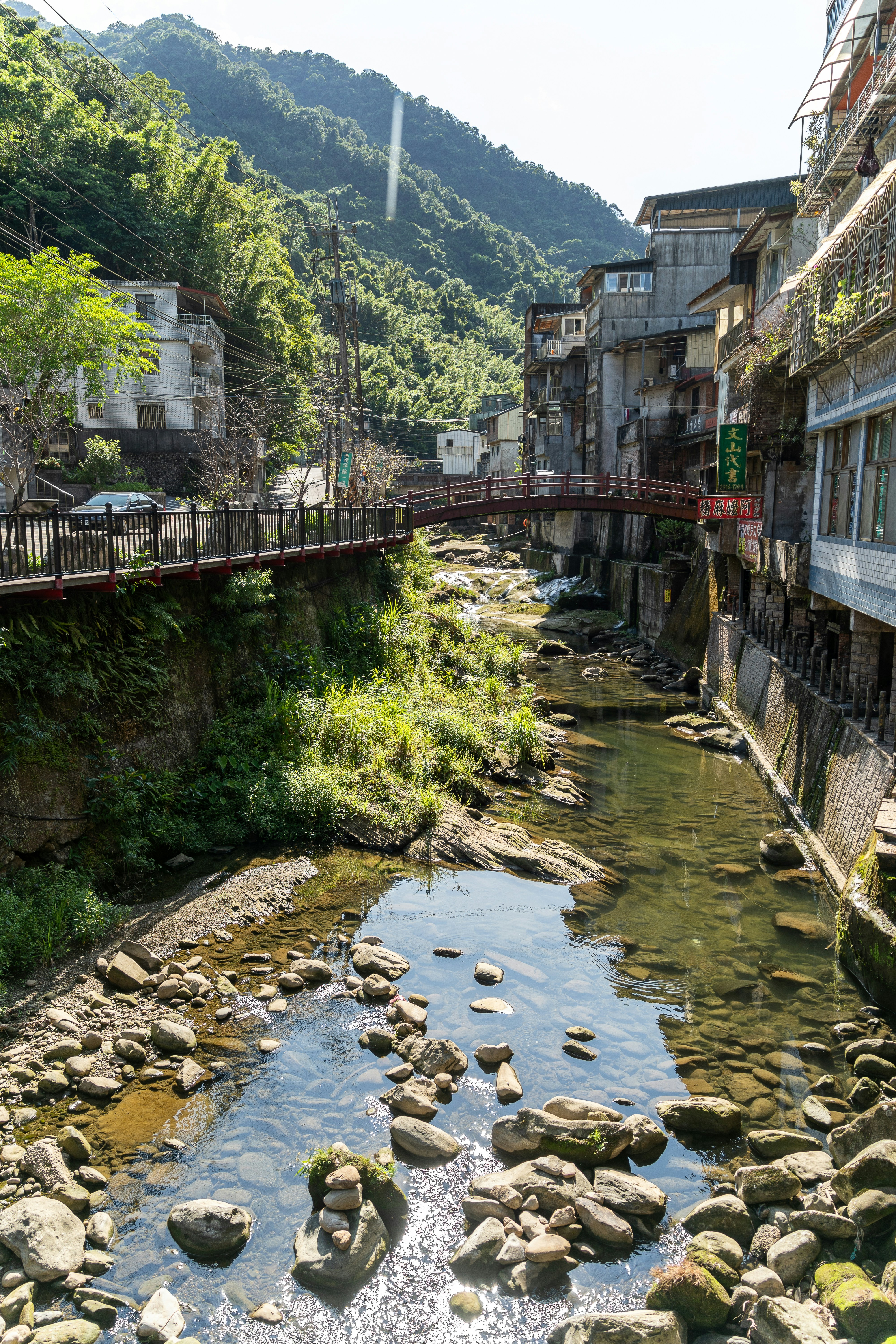River flowing through a village with lush green hills.