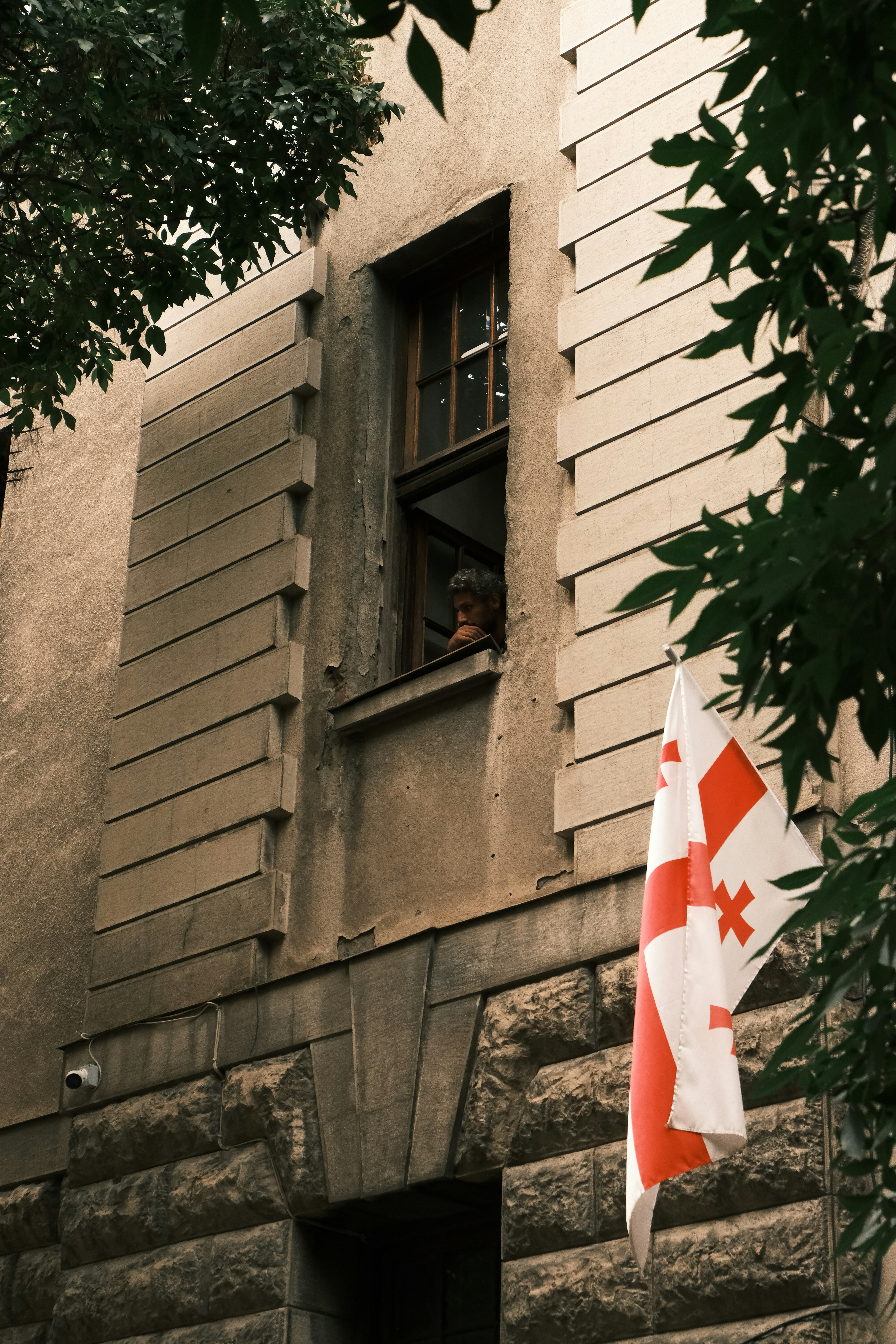 Georgische Flagge hängt vor Gebäude in der Nähe des Fensters