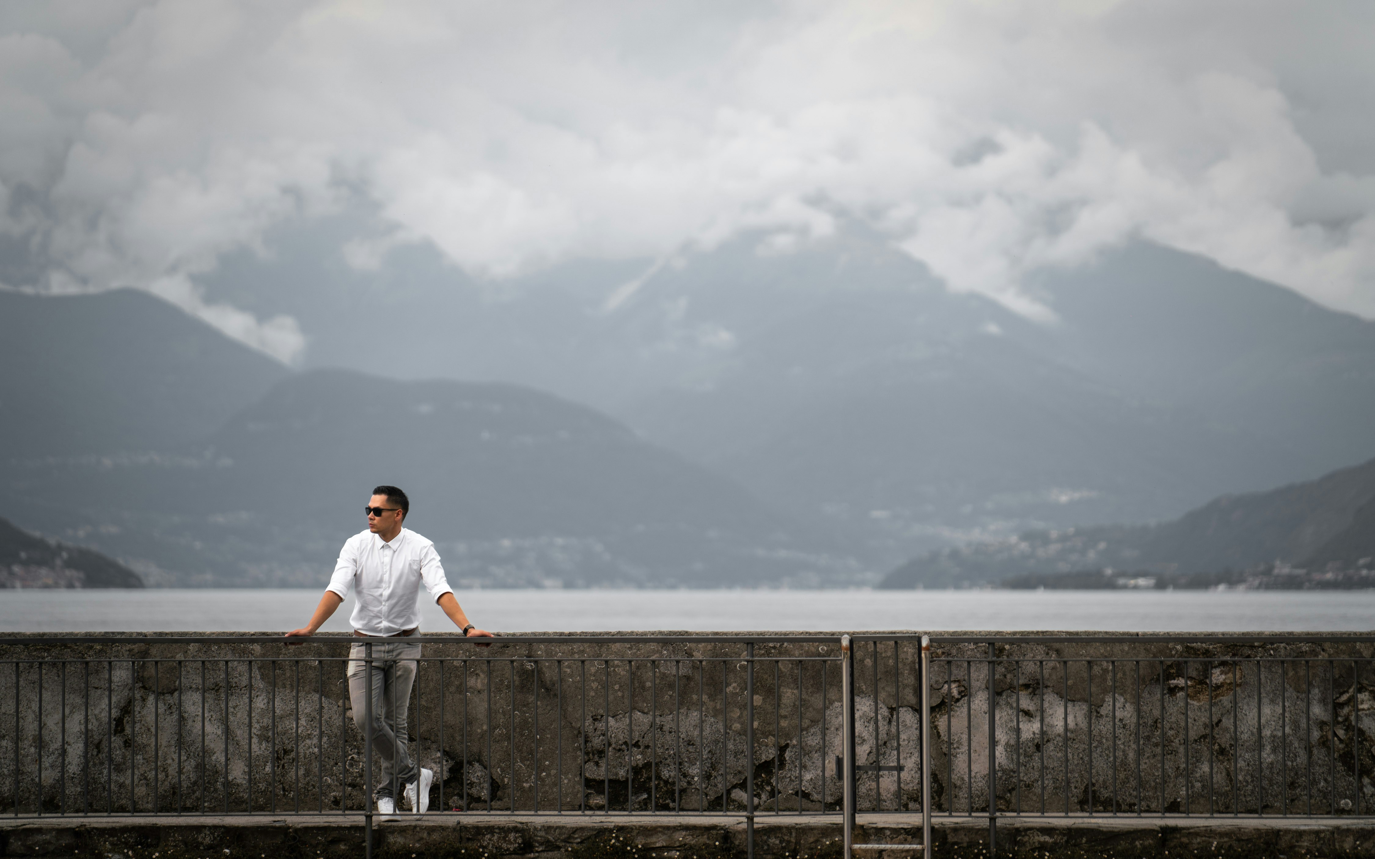 Homme appuyé sur un mur avec des montagnes derrière lui.