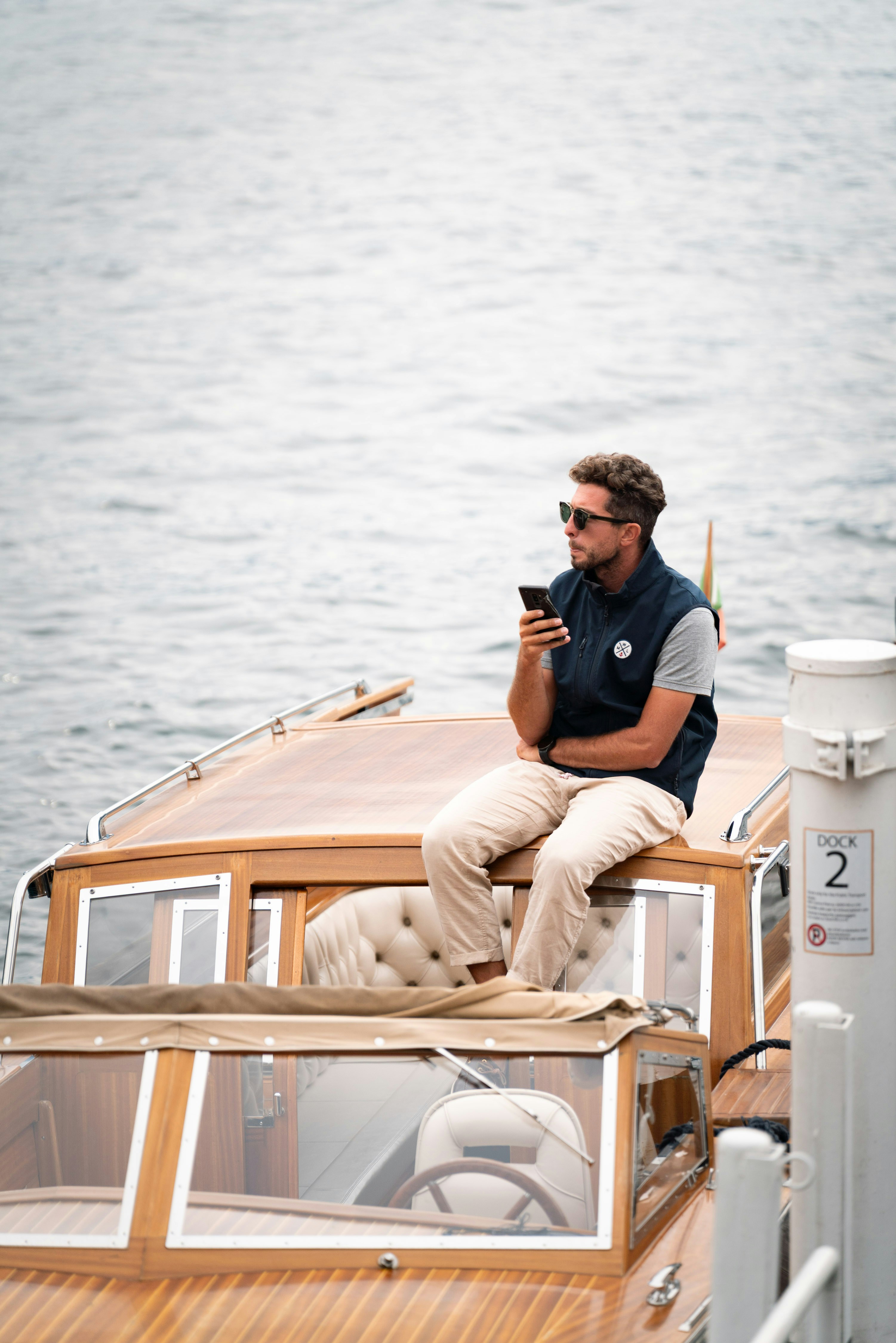 Homme assis sur un bateau utilisant son téléphone.