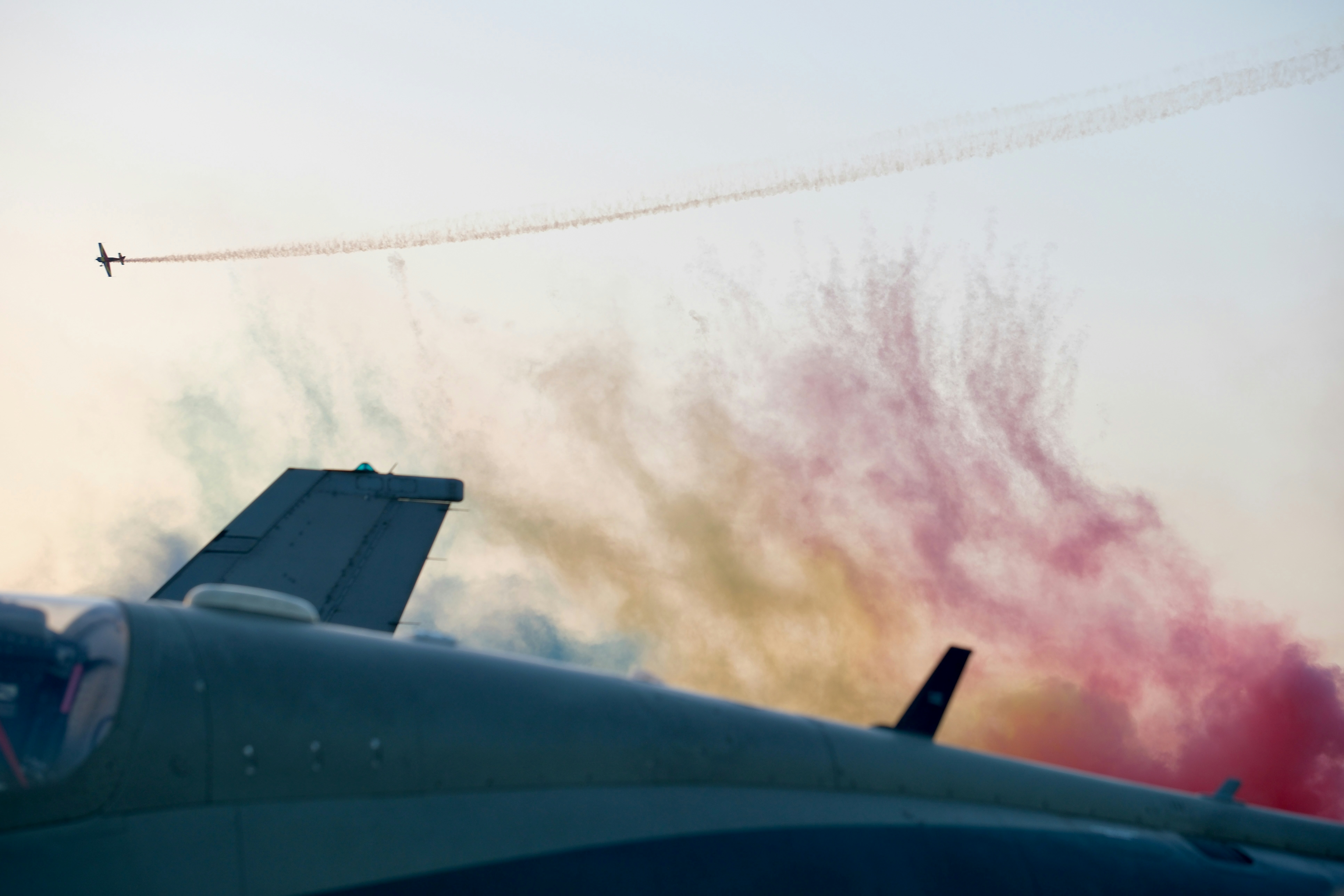 Airplanes trail colored smoke during an airshow.