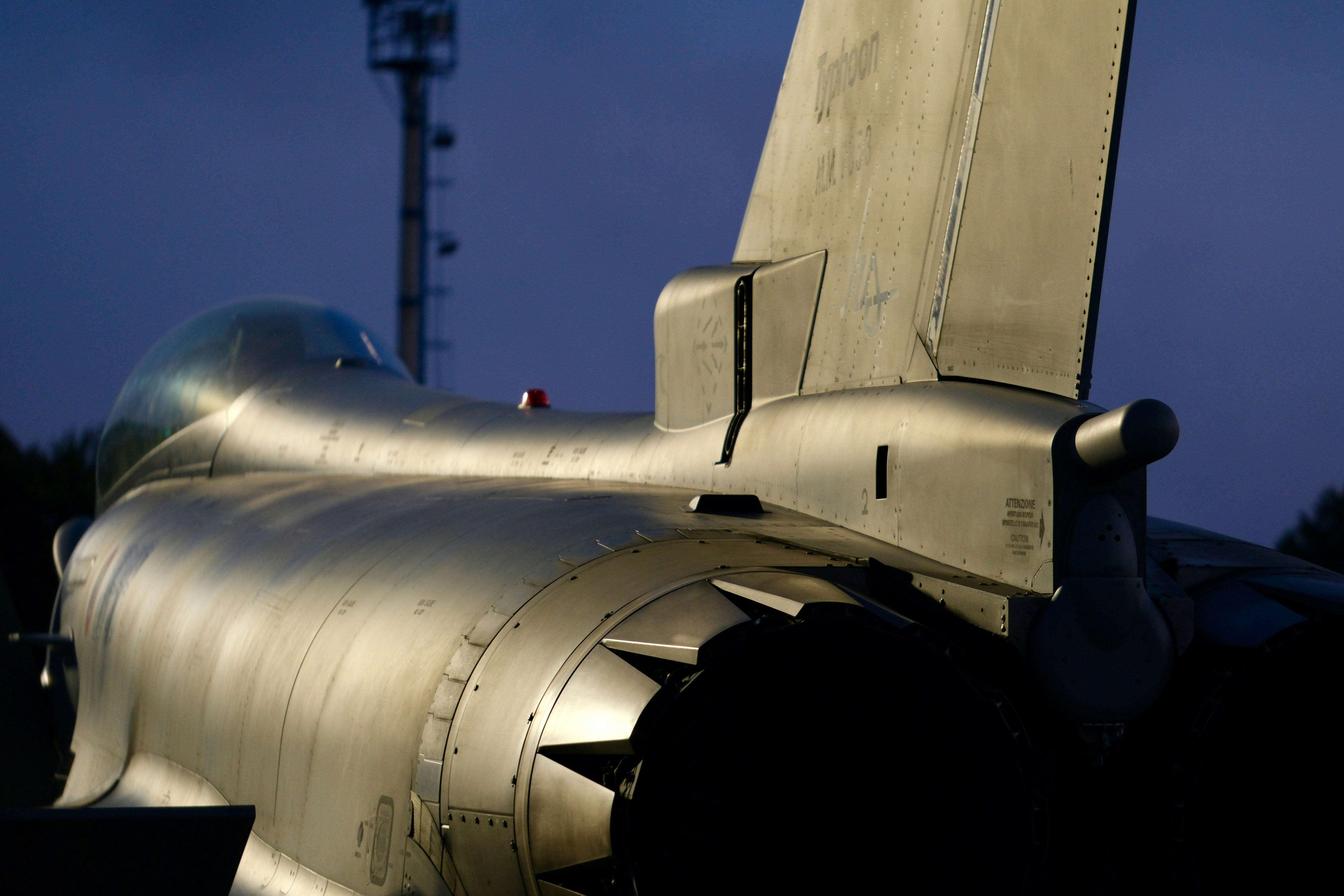 Close-up of a fighter jet's tail section at dusk