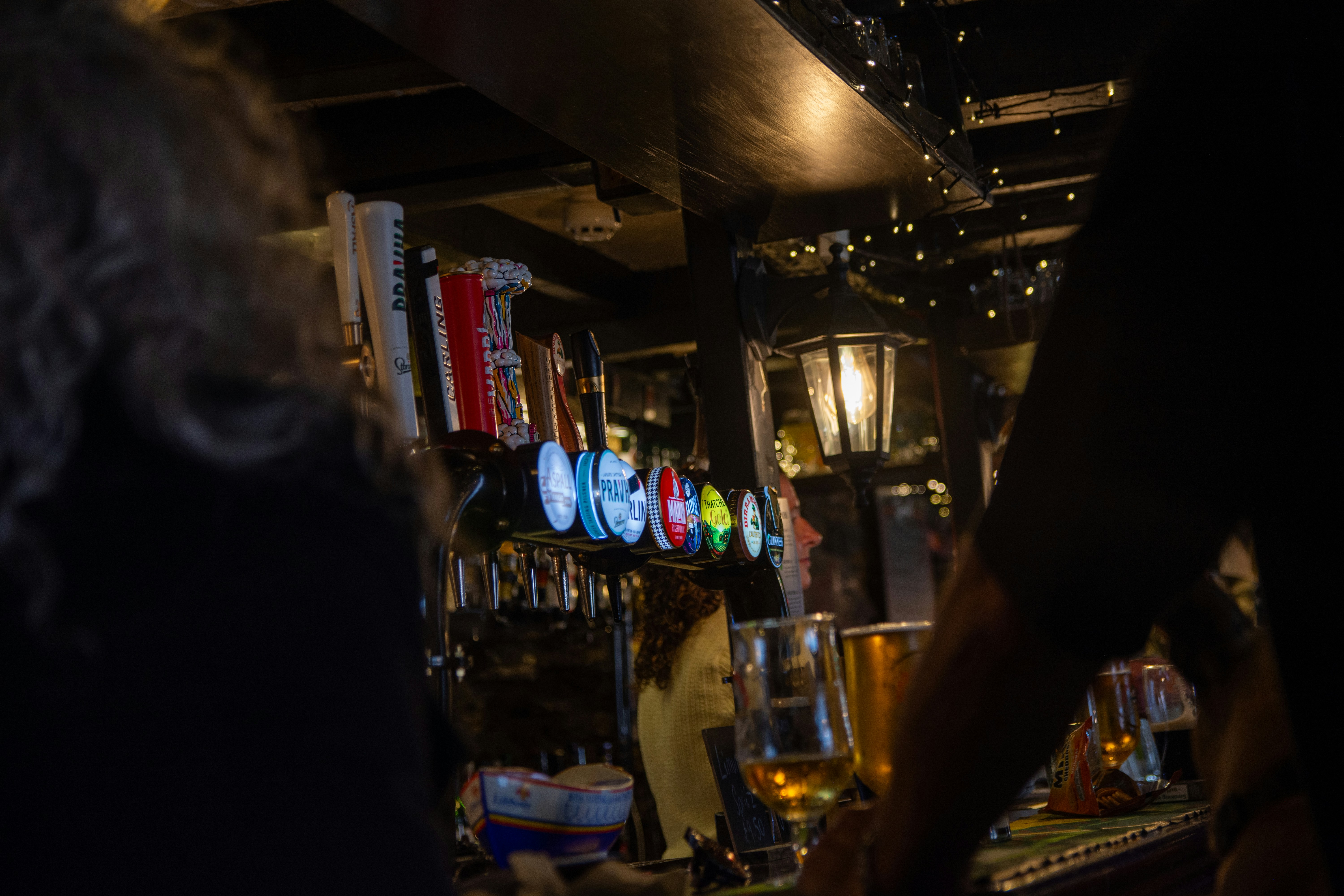 Beer taps and glasses at a dimly lit bar.