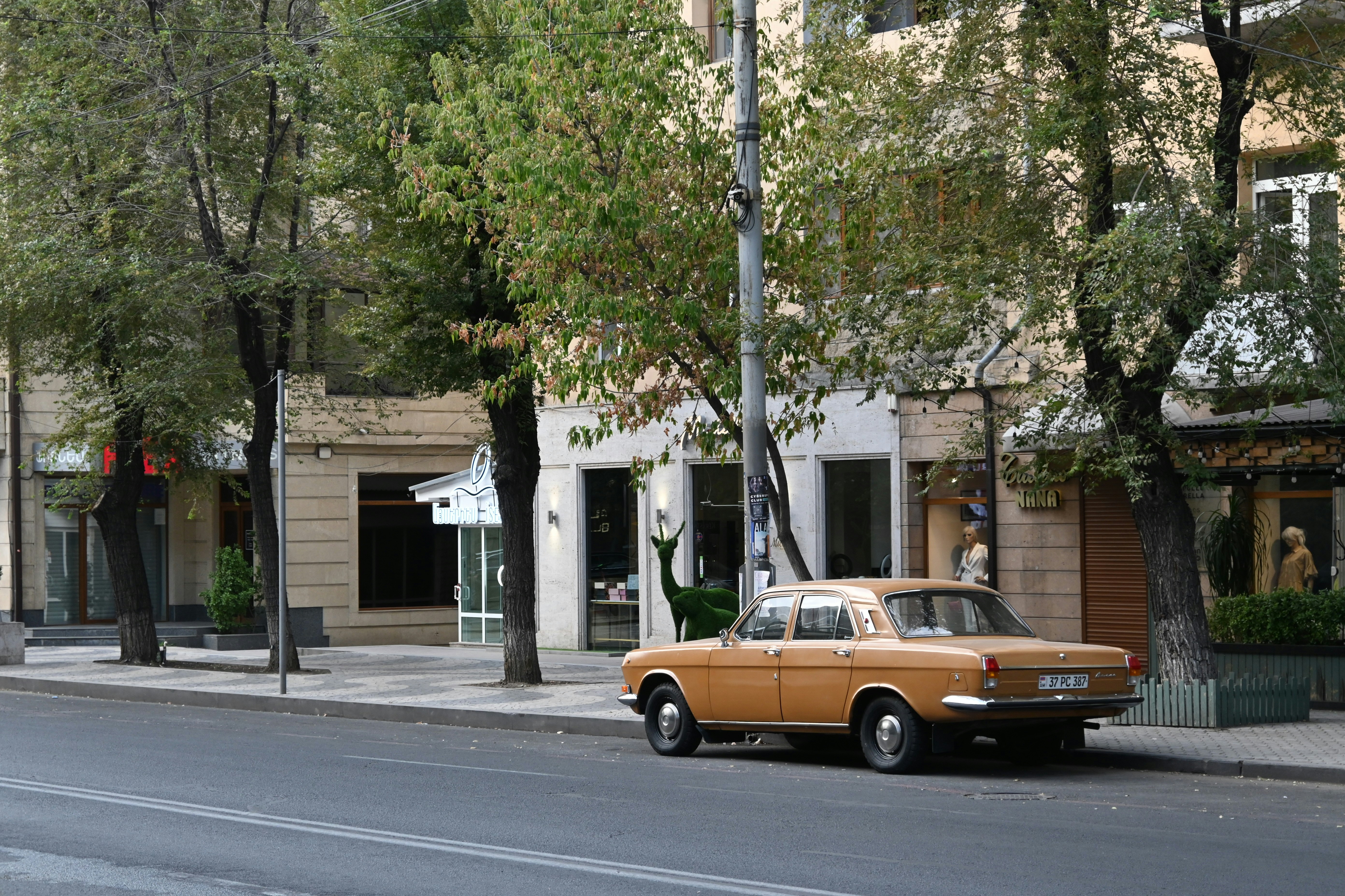 An old orange car parked on a city street.