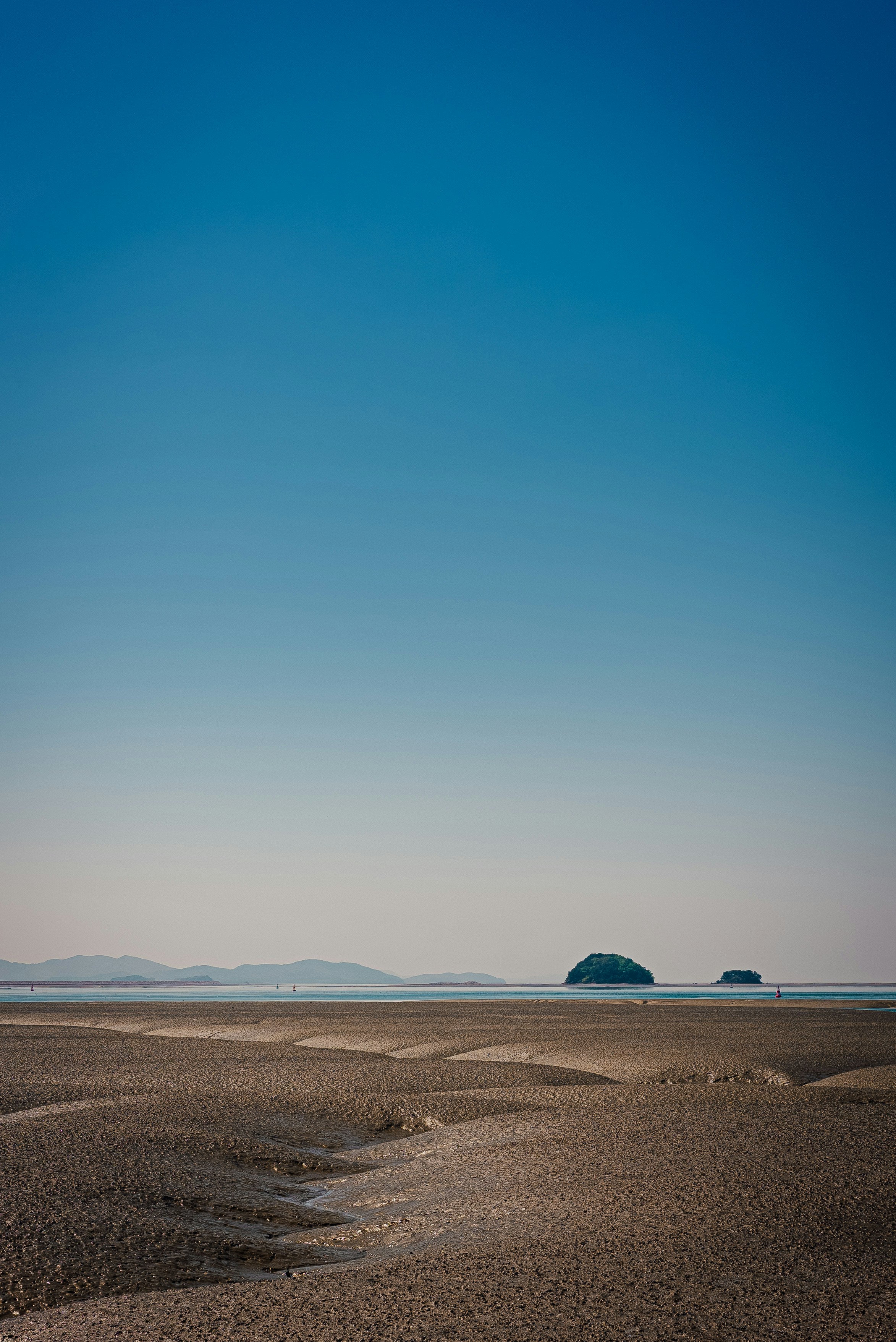 Two small islands in the ocean under clear sky.