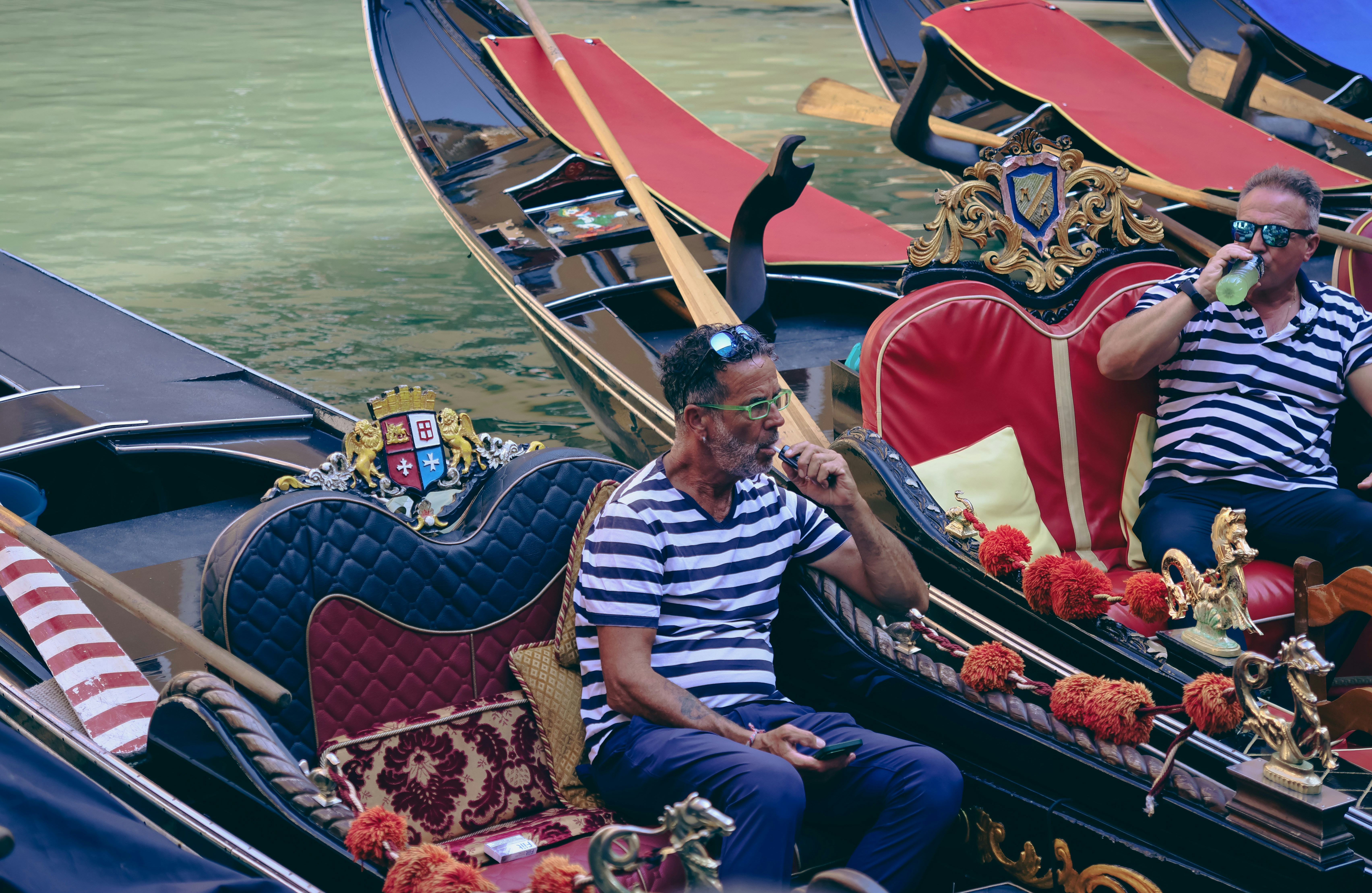 Dois gondoleiros em camisas listradas em gôndolas venezianas.
