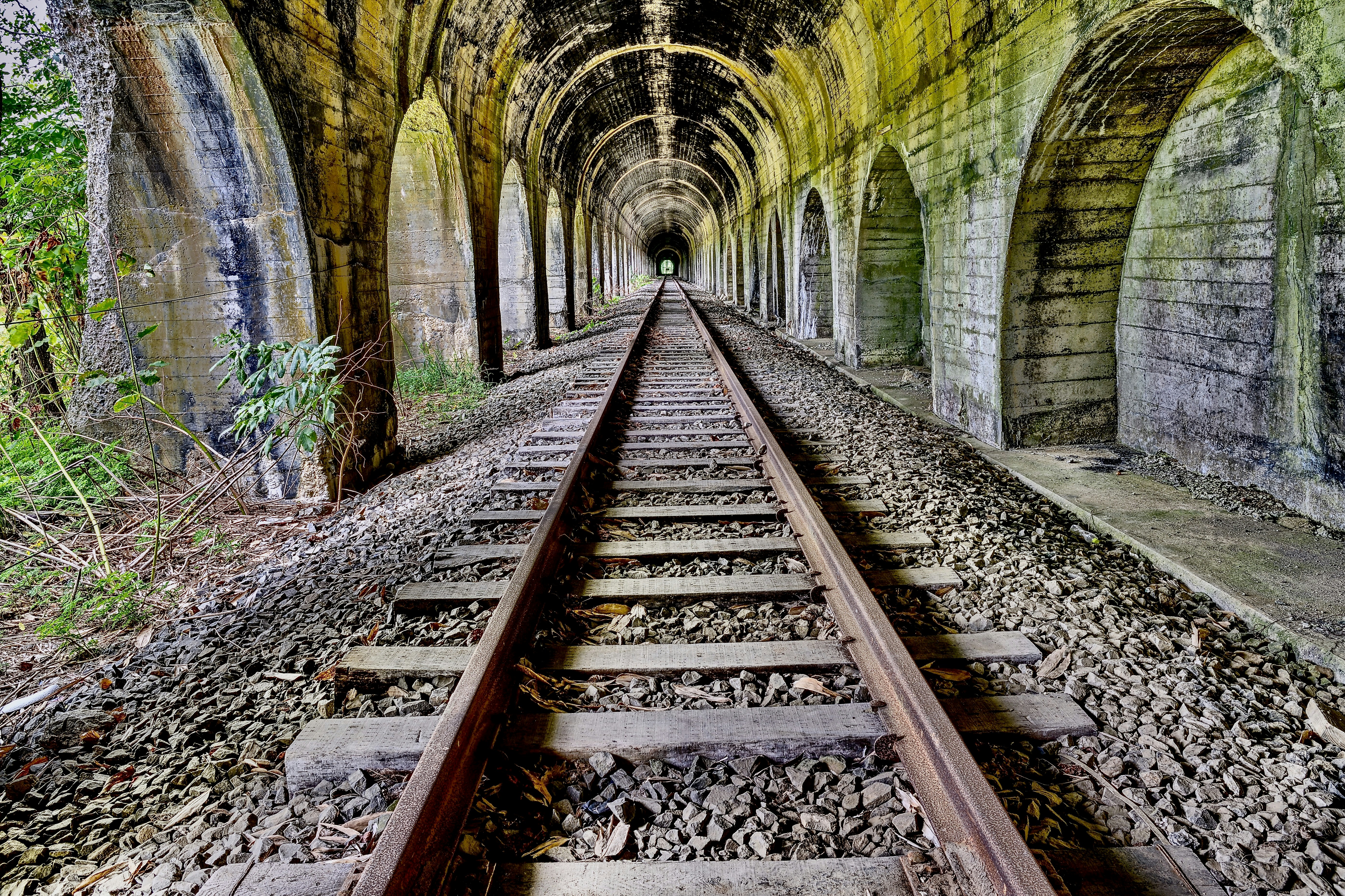 Old stone railway tunnel with tracks leading into distance
