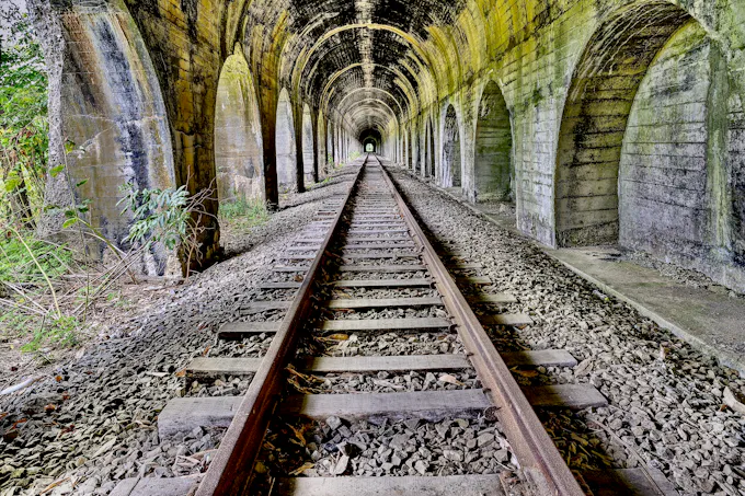Old stone railway tunnel with tracks leading into the distance, similar to the historic Gallitzin Tunnels that give Tunnelhill, PA its name