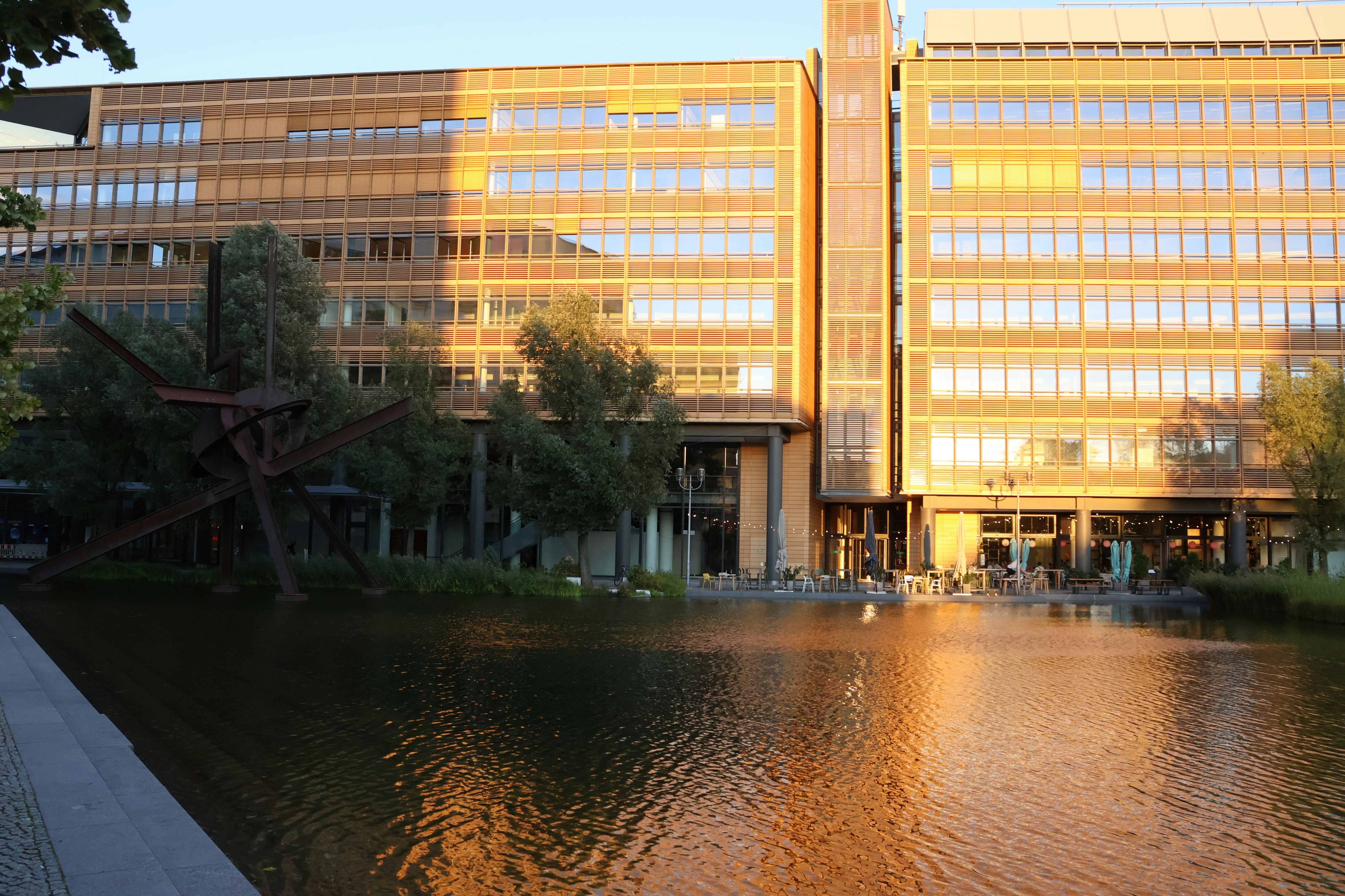 Modern building reflected in calm water at sunset