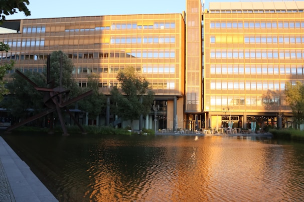 Modern building reflected in calm water at sunset