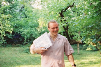 Man holding a map in a lush garden.