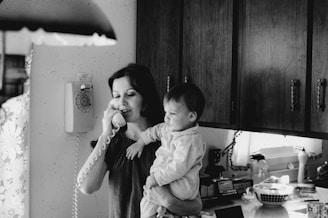 Woman holding baby while talking on phone.