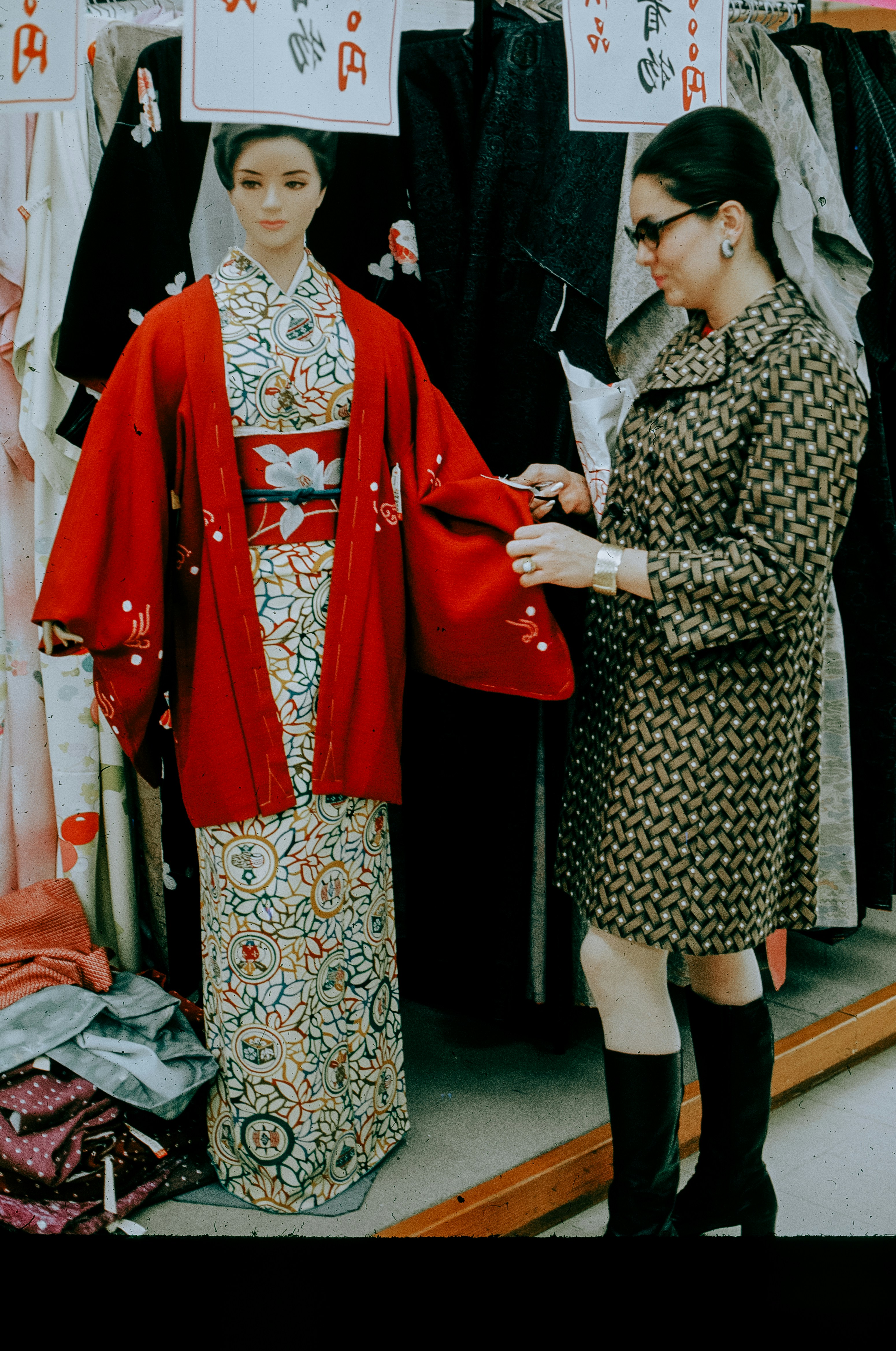 Woman examines kimono on mannequin in store.