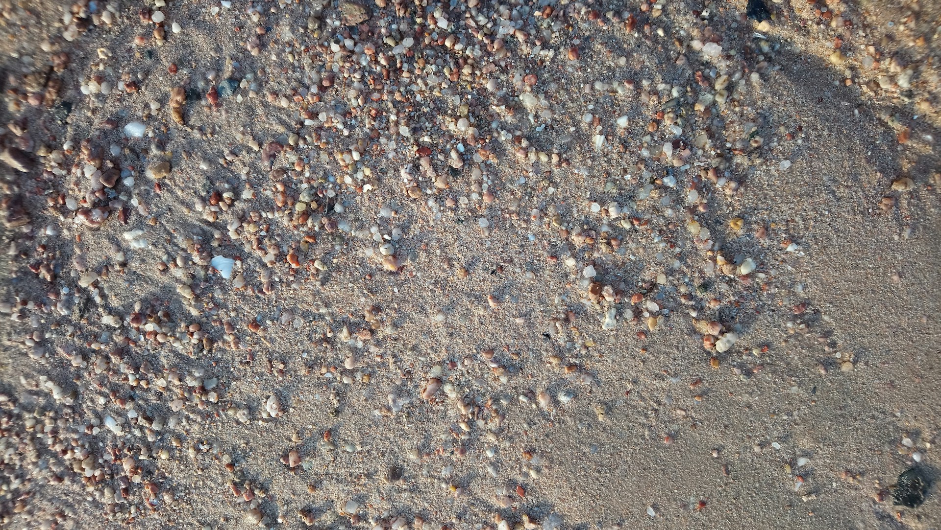 Close-up of sand and small pebbles on a beach.