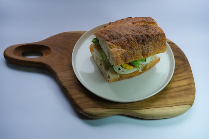 A sandwich on a plate on a wooden board