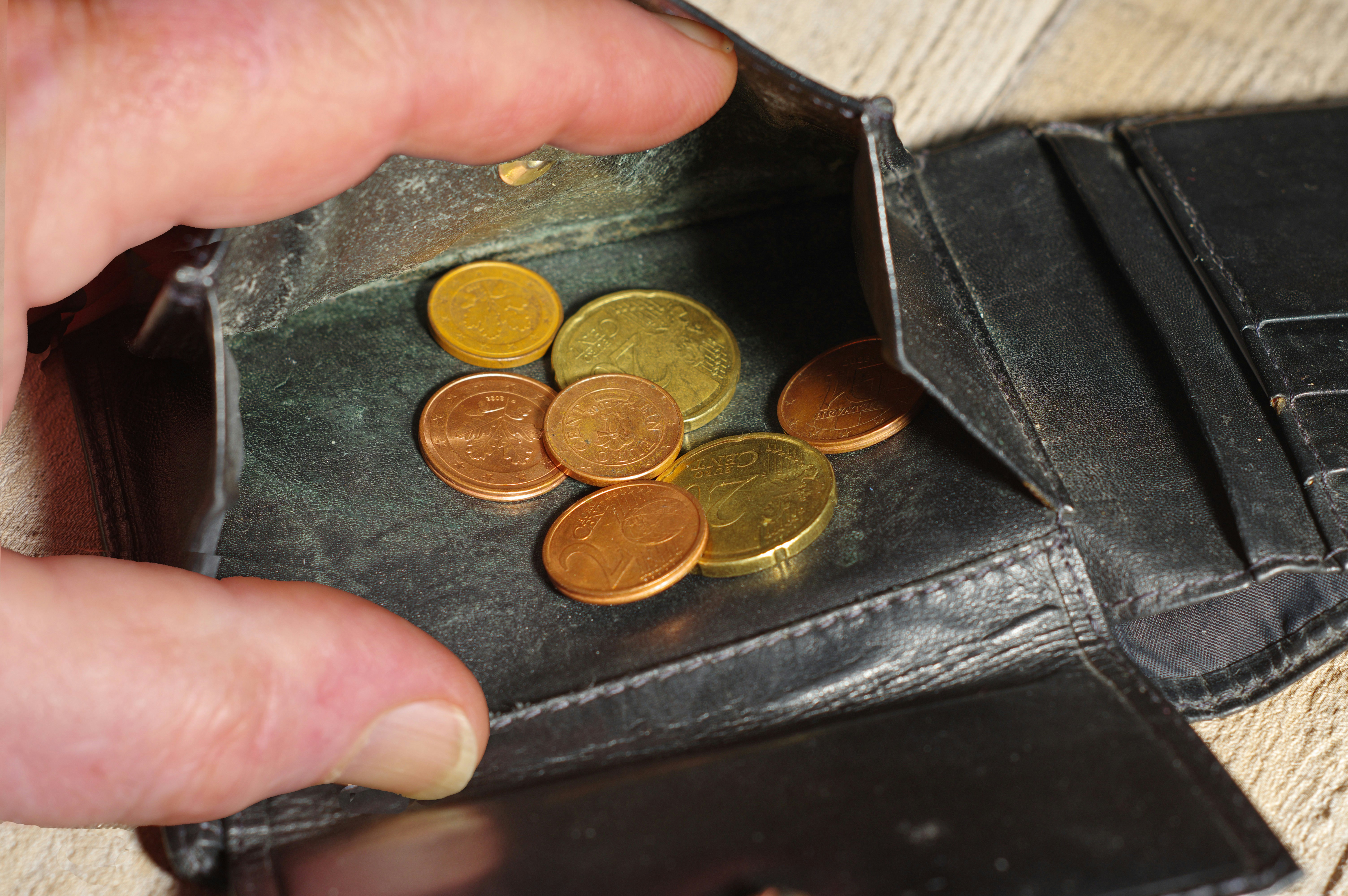 Hand placing coins into an open wallet