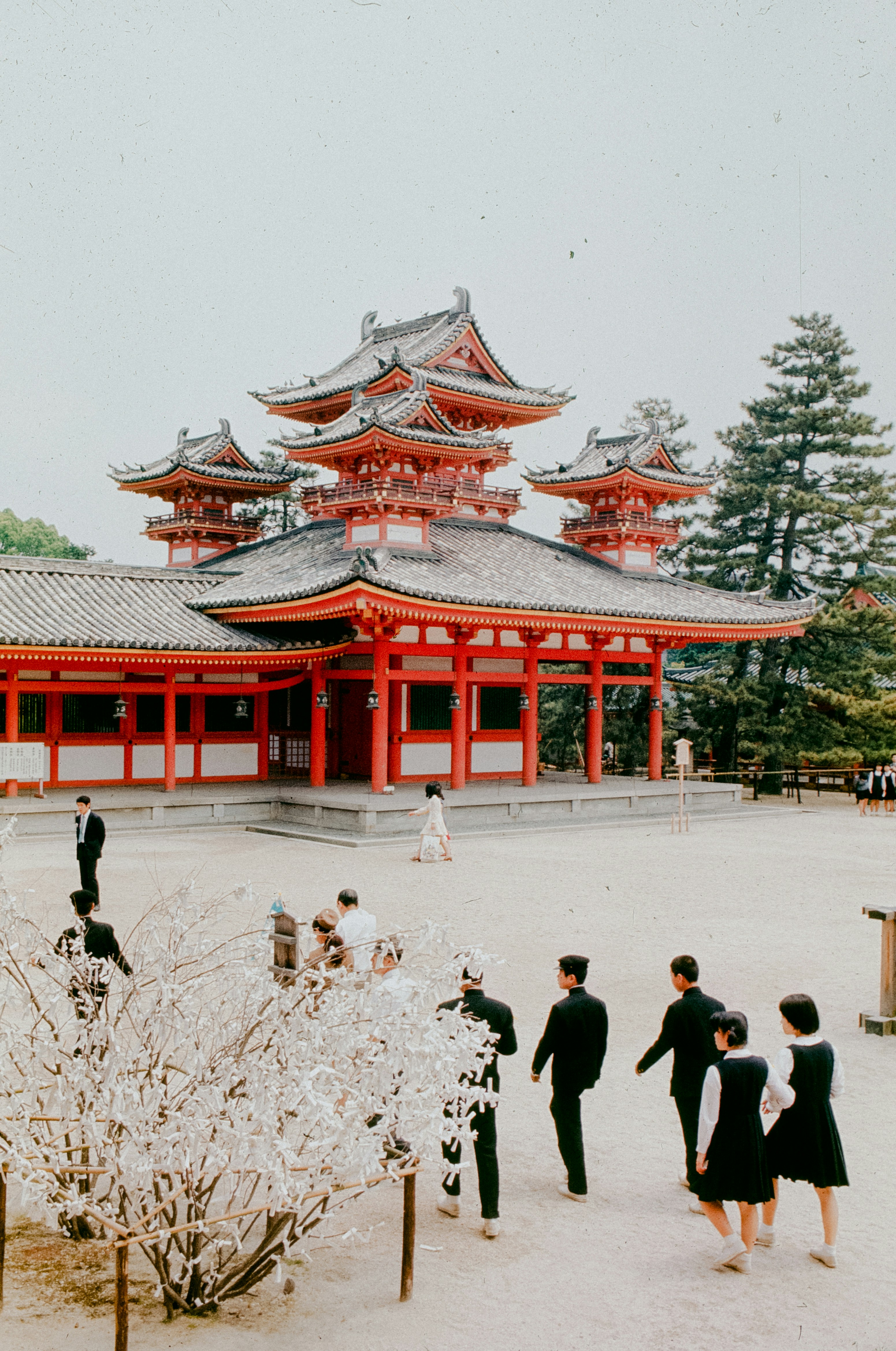Traditional japanese temple with people walking in courtyard.