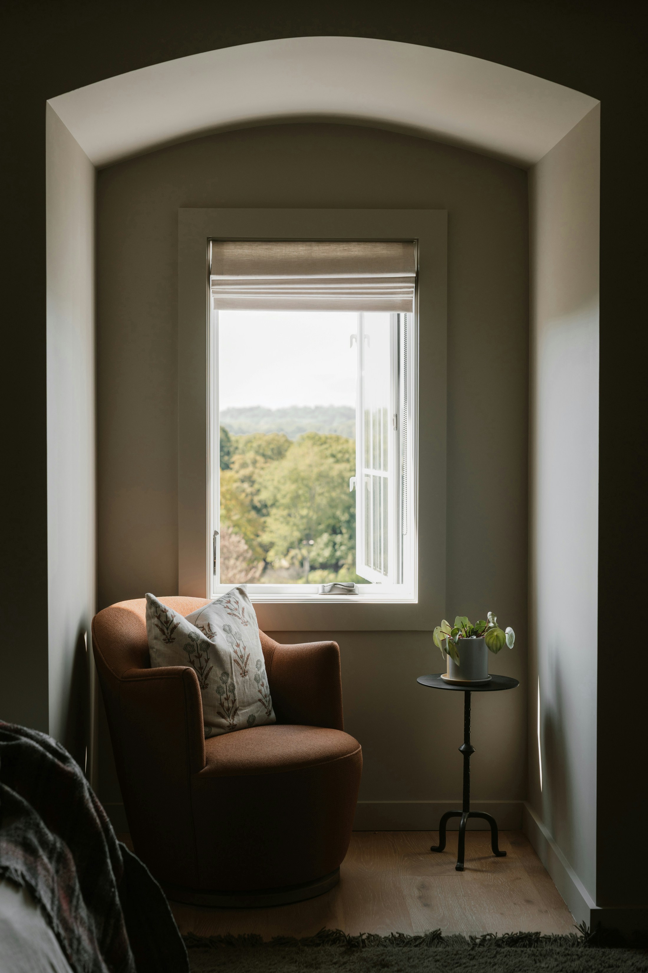 Cozy armchair by a window with a garden view.