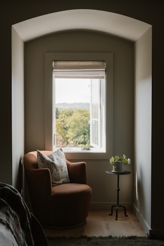Cozy armchair by a window with a garden view.