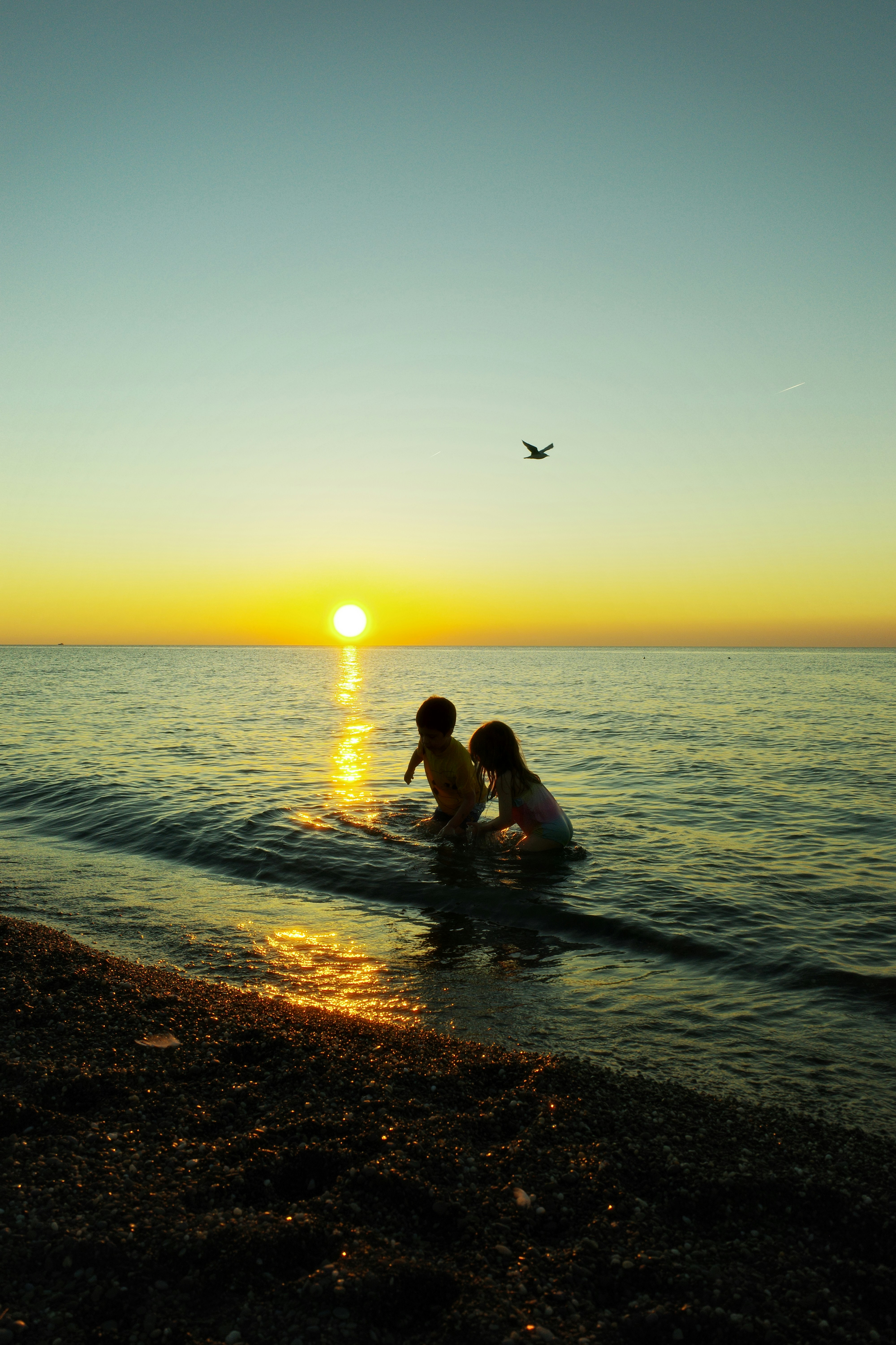 Los niños juegan en el océano al atardecer.