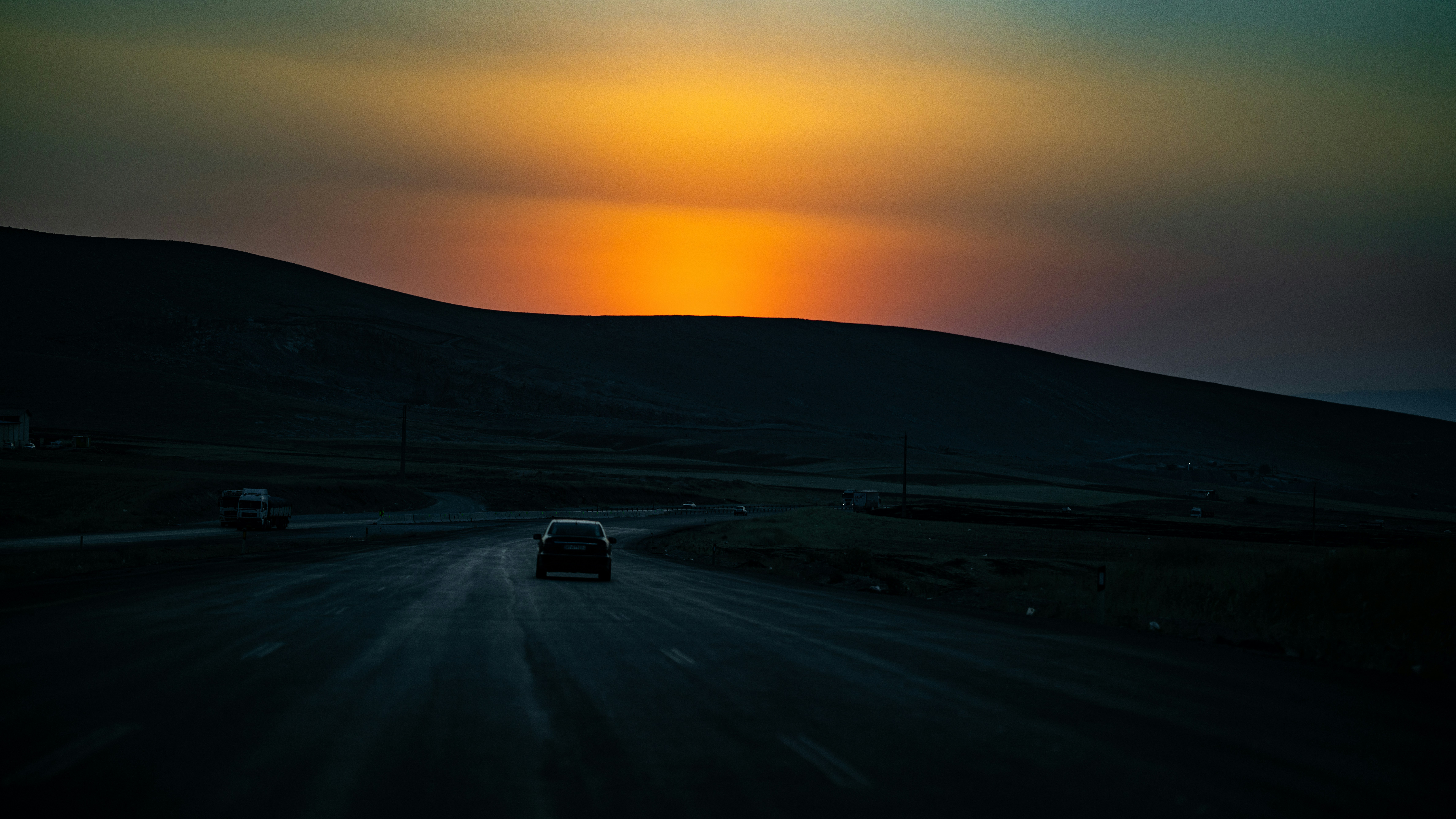 L'auto guida su strada verso un tramonto vibrante.