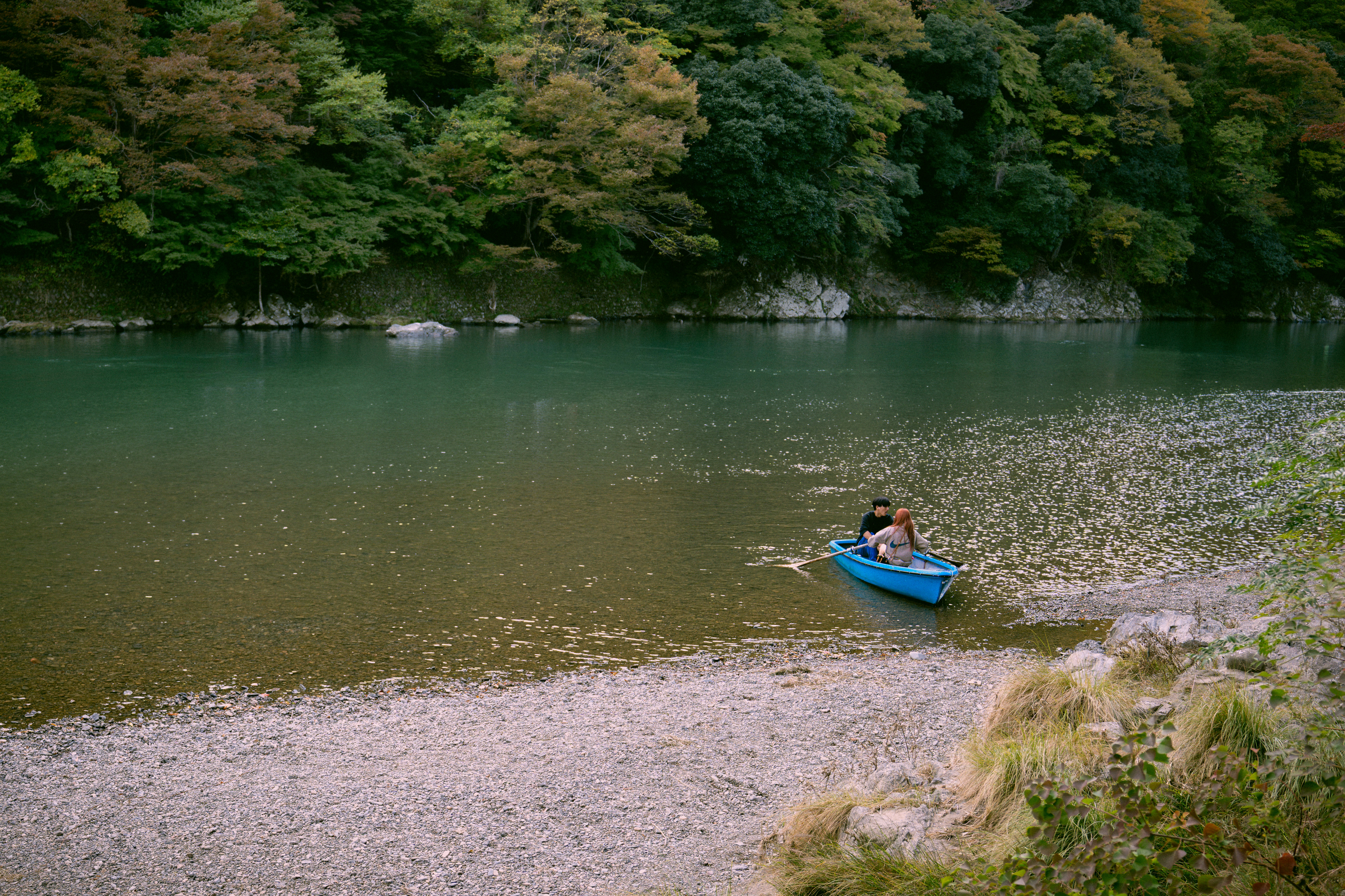 Person in a blue kayak on a rocky shore.