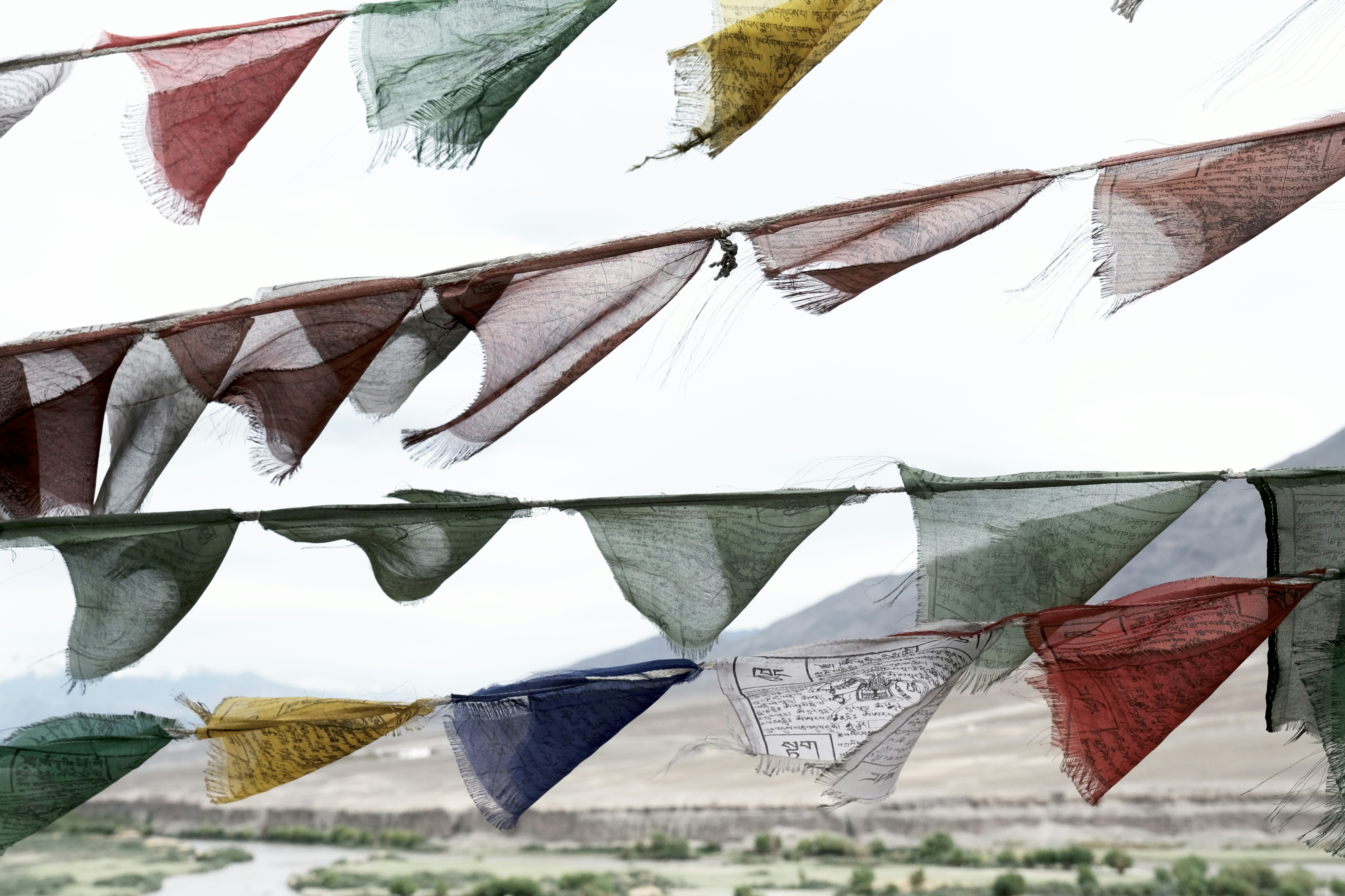 Colorful prayer flags flutter against a cloudy sky.