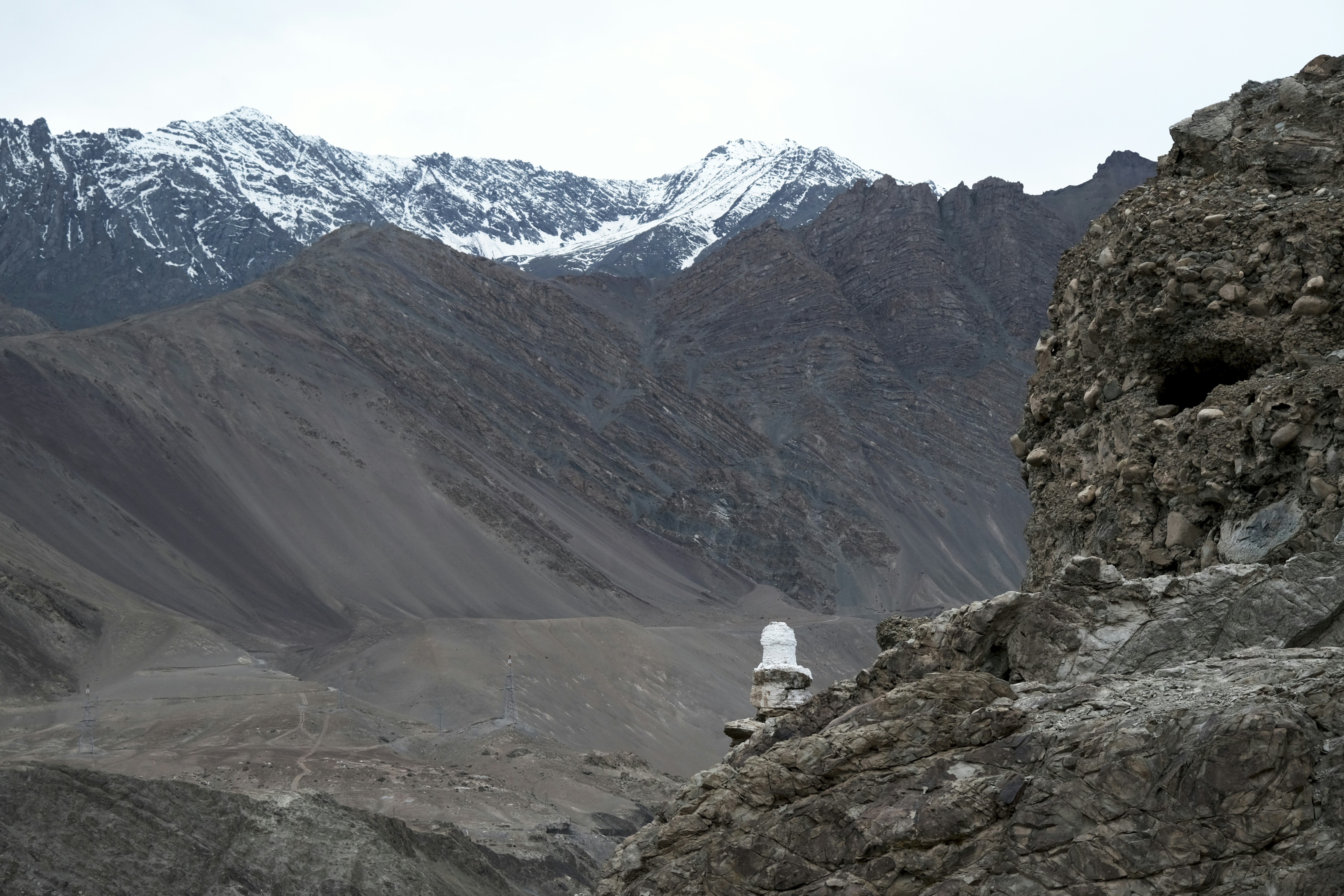 Snow-capped mountains rise behind a barren, rocky landscape.