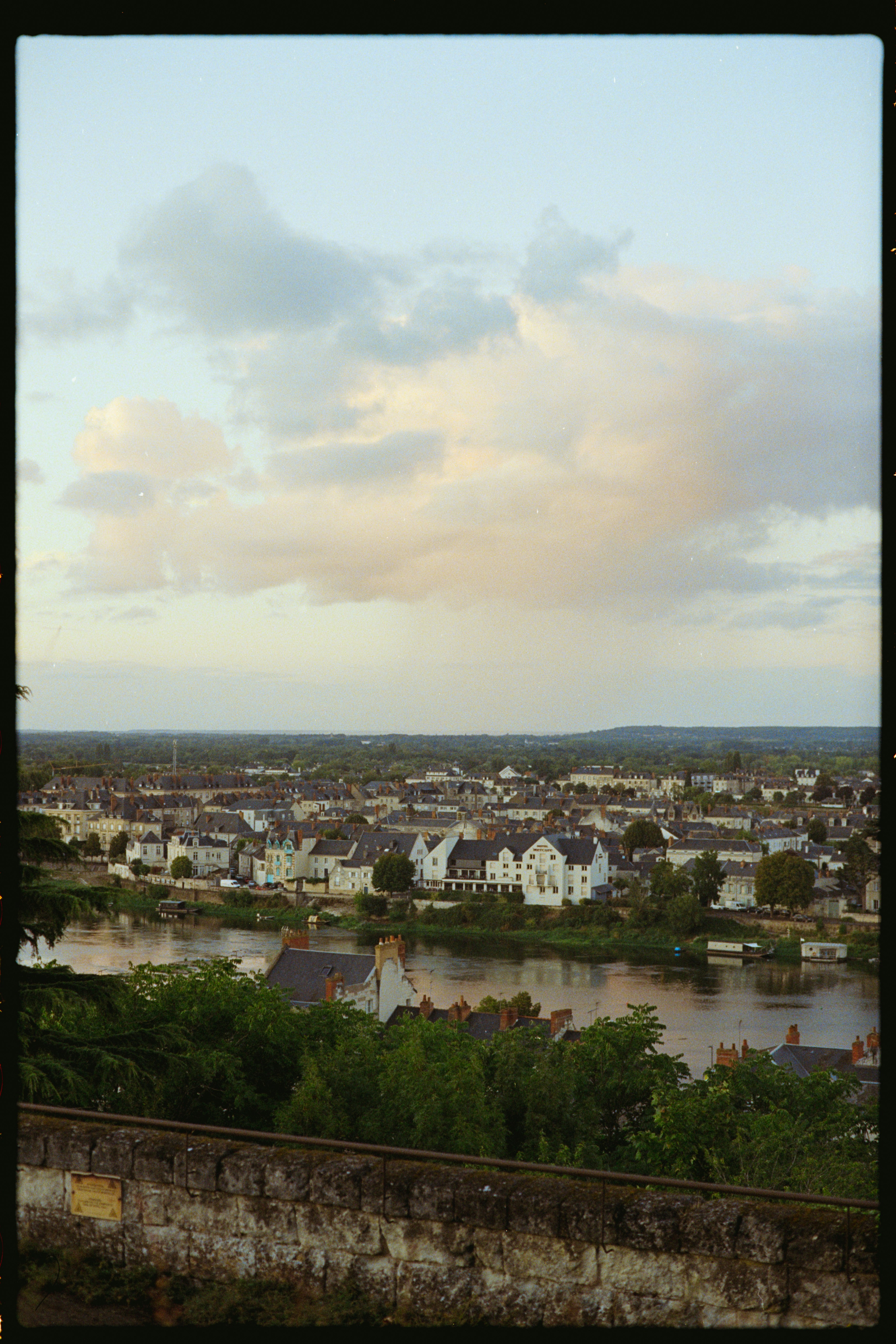 Town on riverbank with white buildings under cloudy sky