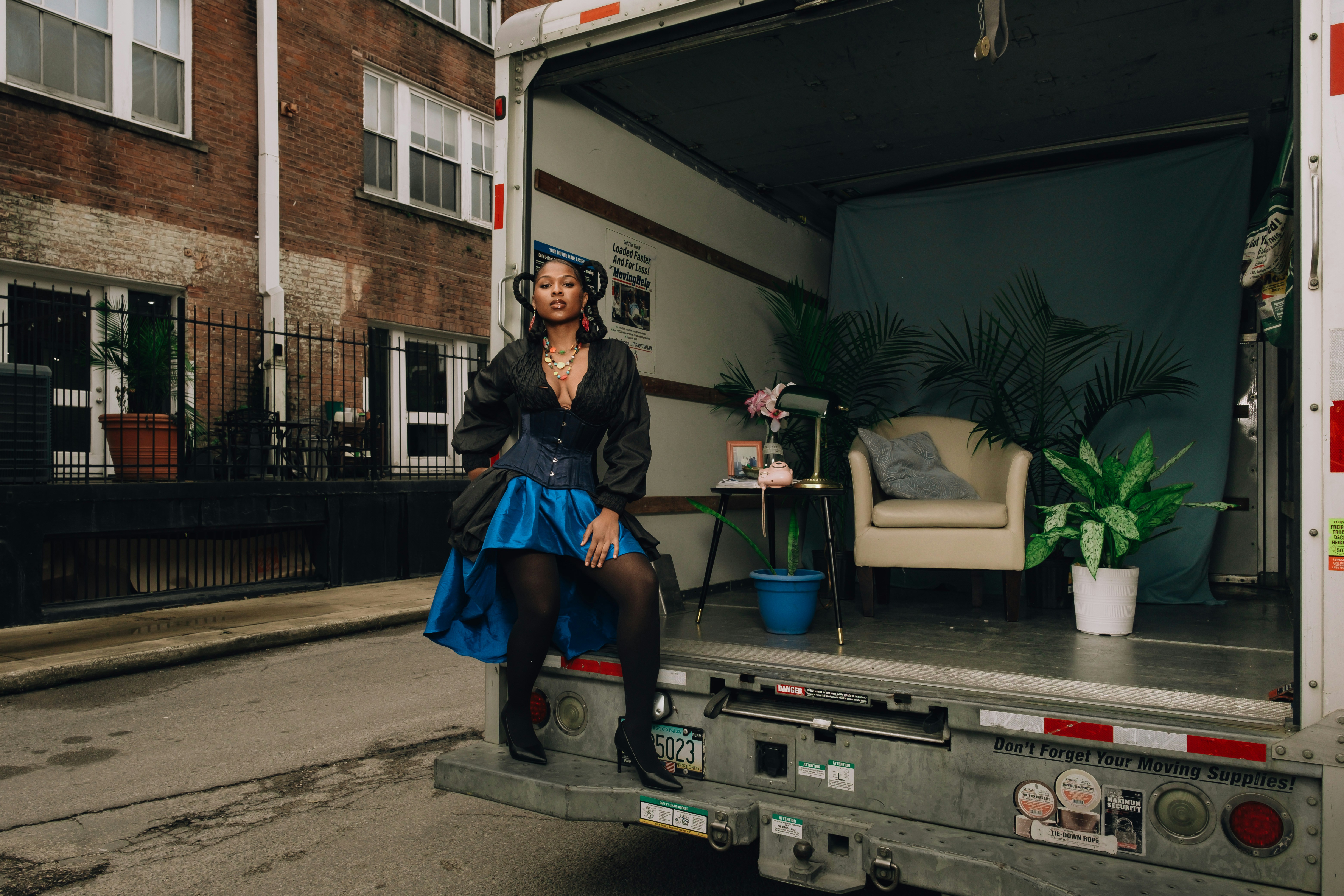 Woman in blue and black outfit sits in truck