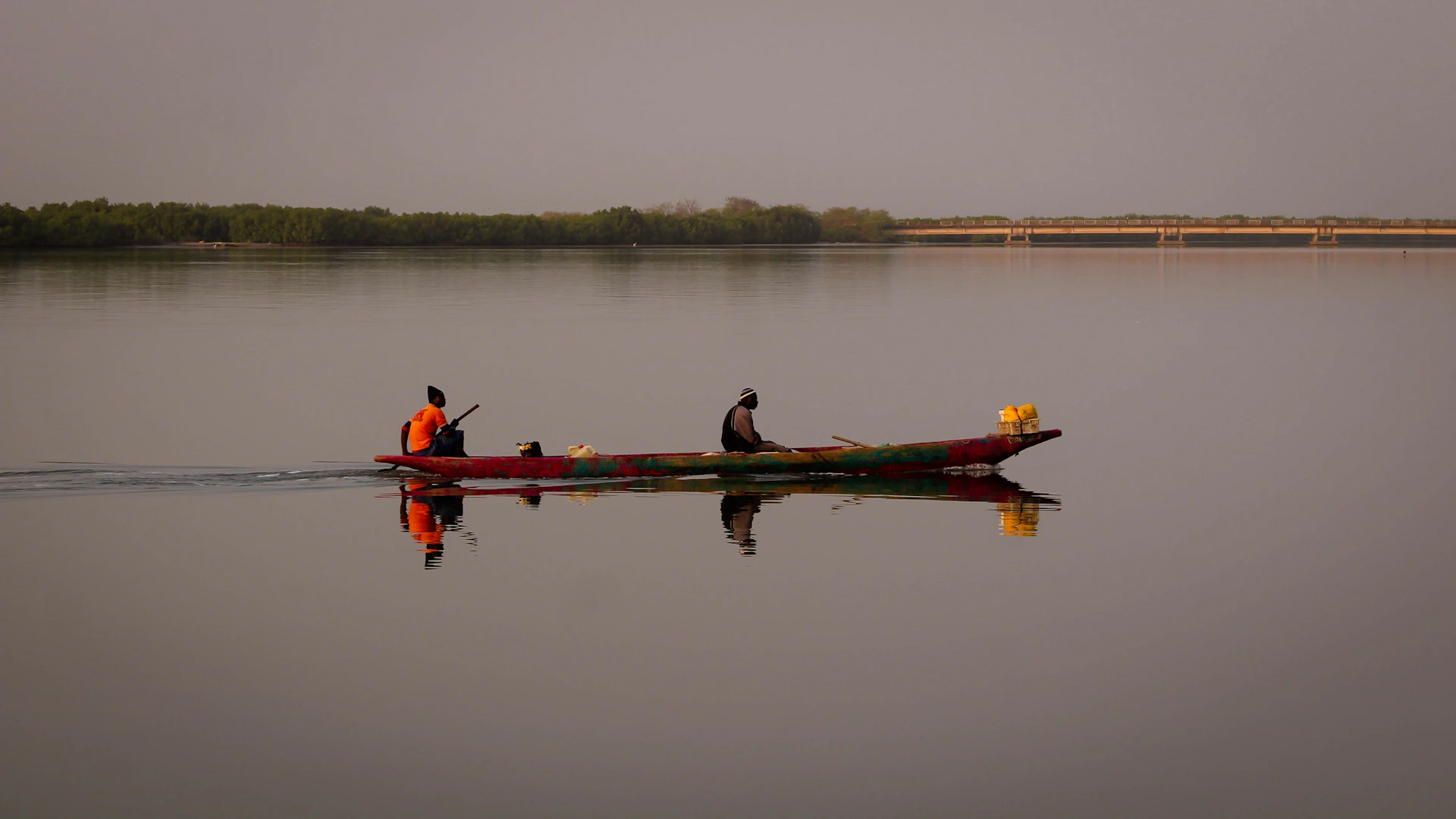 Two people in a long boat on calm water