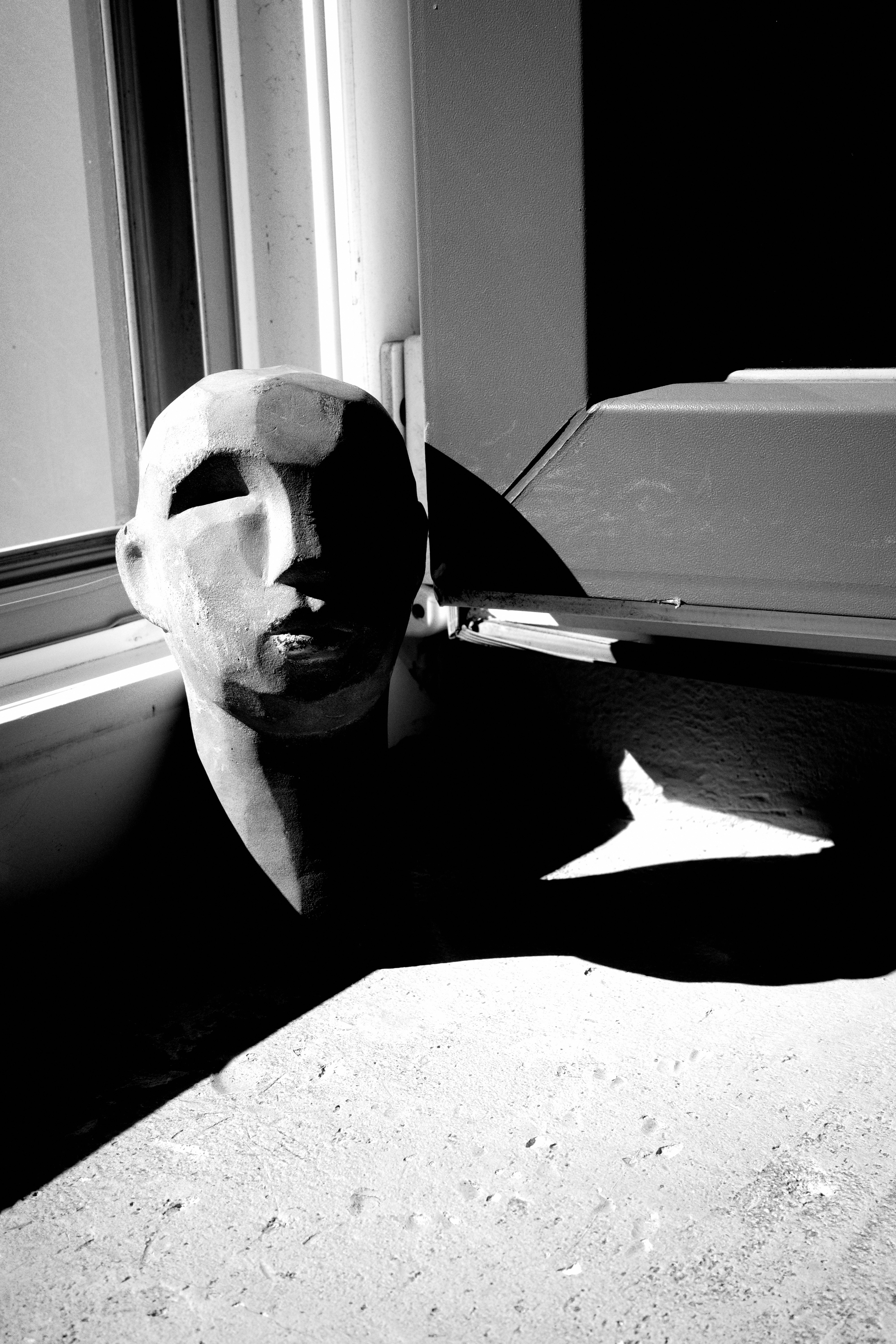 A wooden head sculpture cast in dramatic shadow.