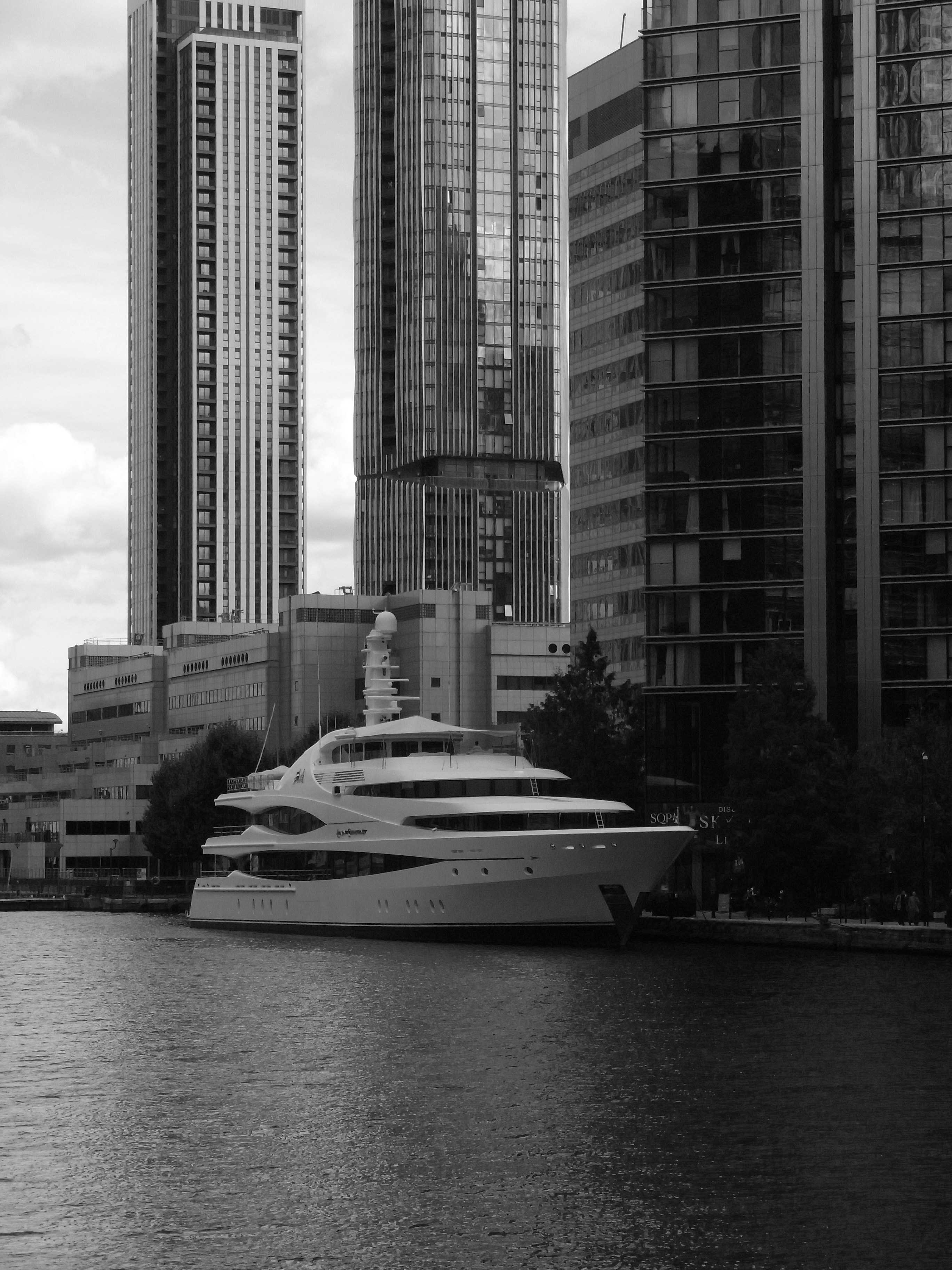 Yacht di lusso ormeggiato vicino a moderni grattacieli sull'acqua.
