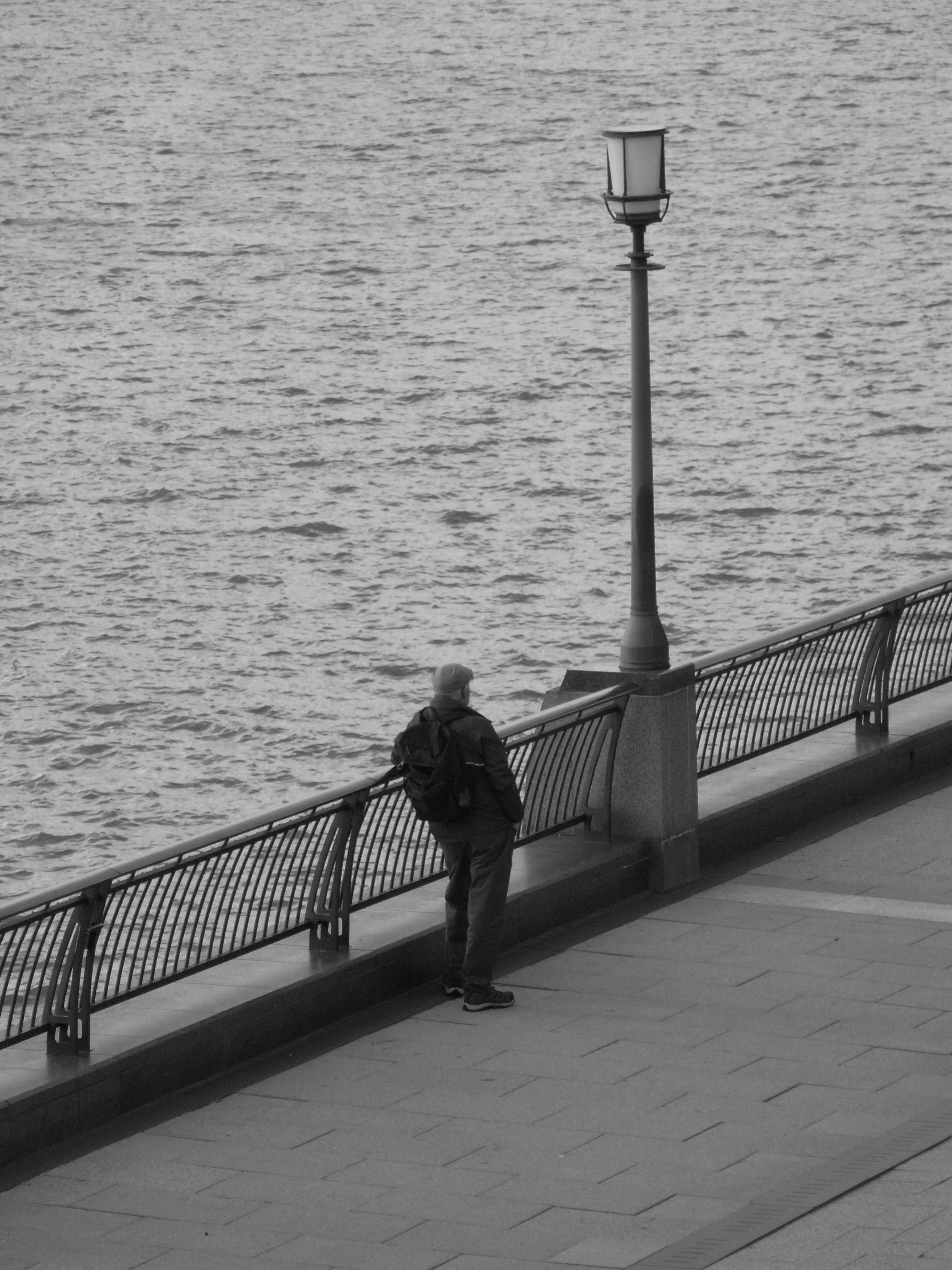 Man standing by railing next to water photo – Free Image on Unsplash