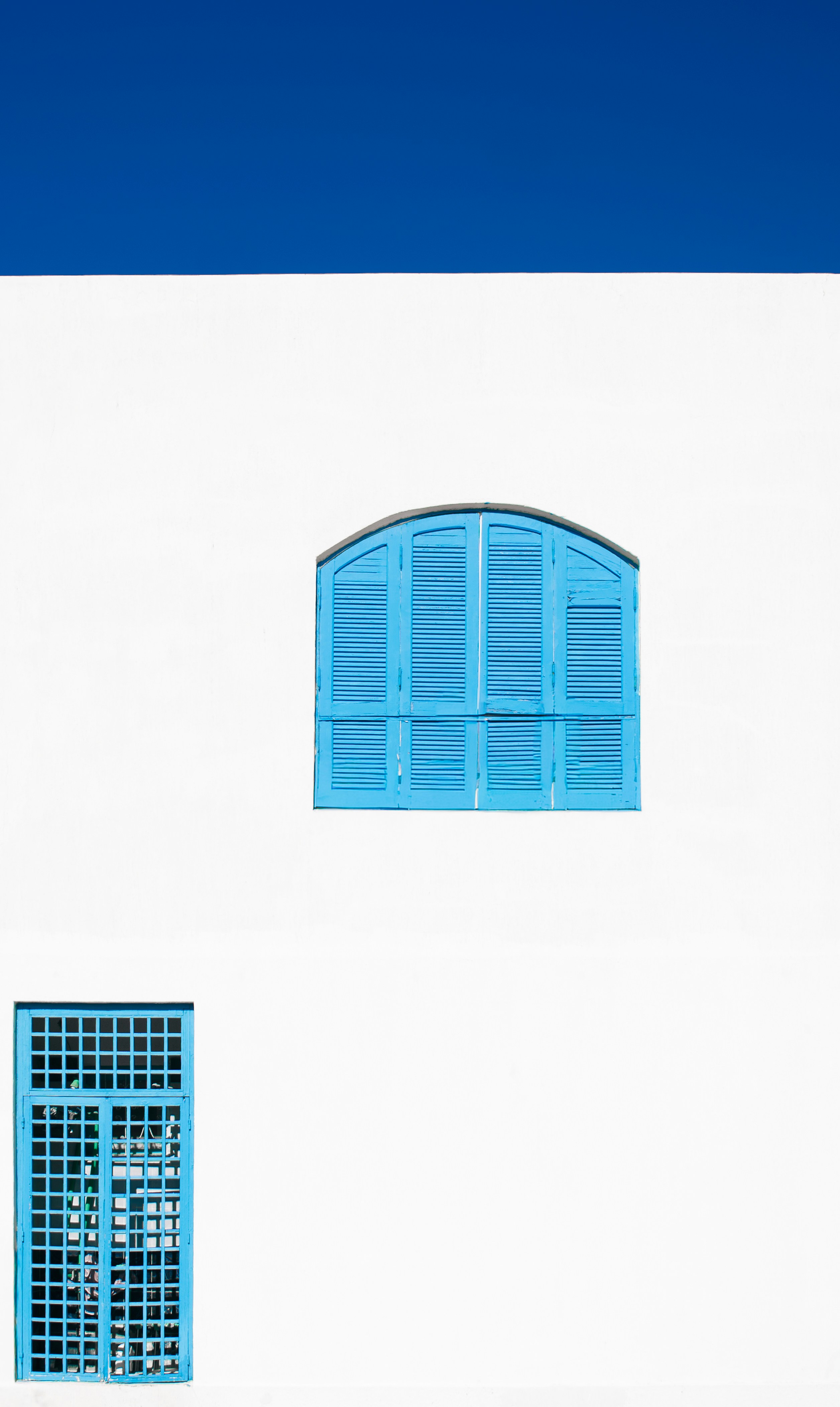 Pared blanca con persianas azules y ventana.