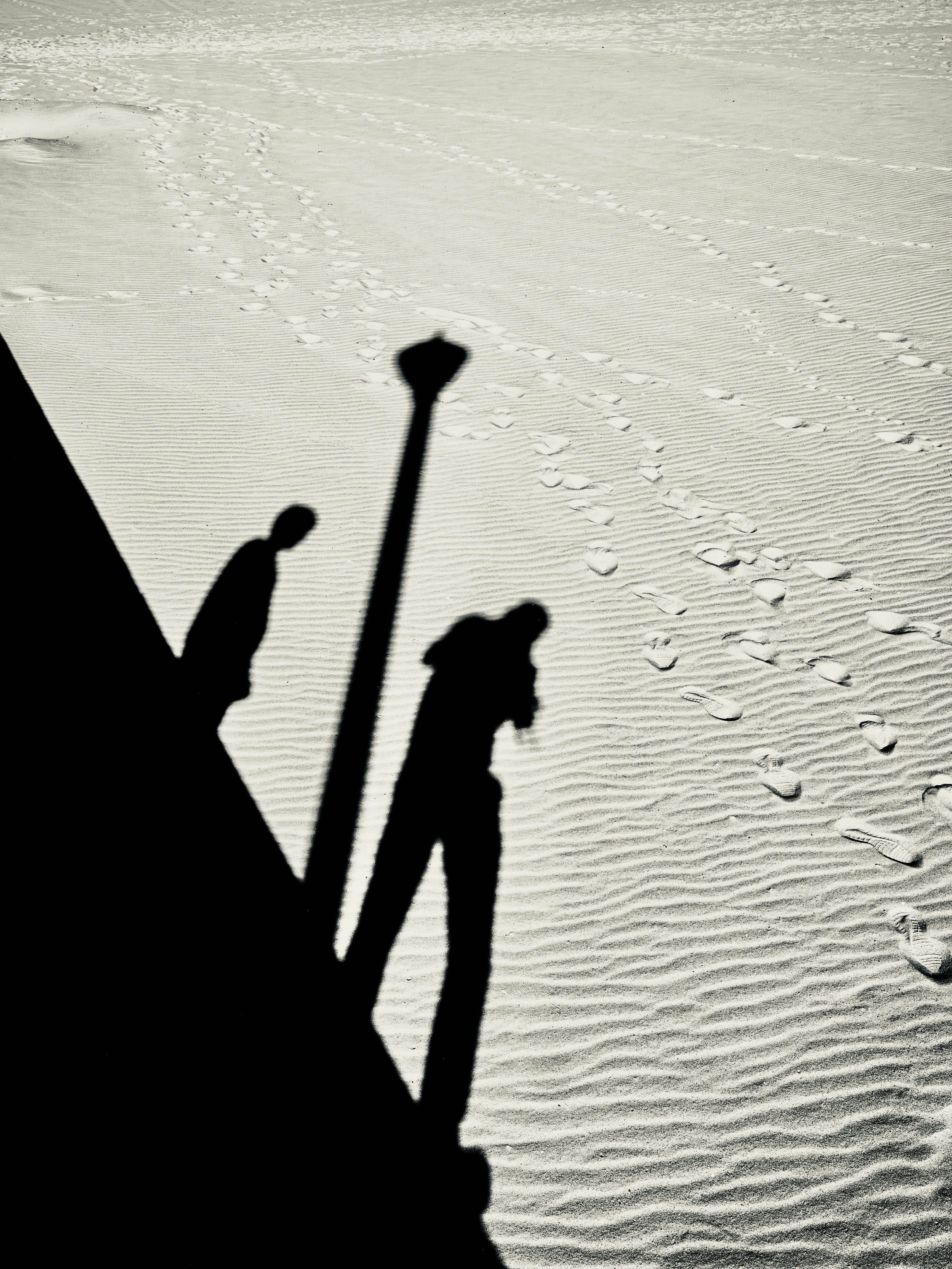 Shadows of people and lamppost on sandy dunes