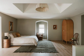 A neutral bedroom with a large bed and wooden wardrobe.