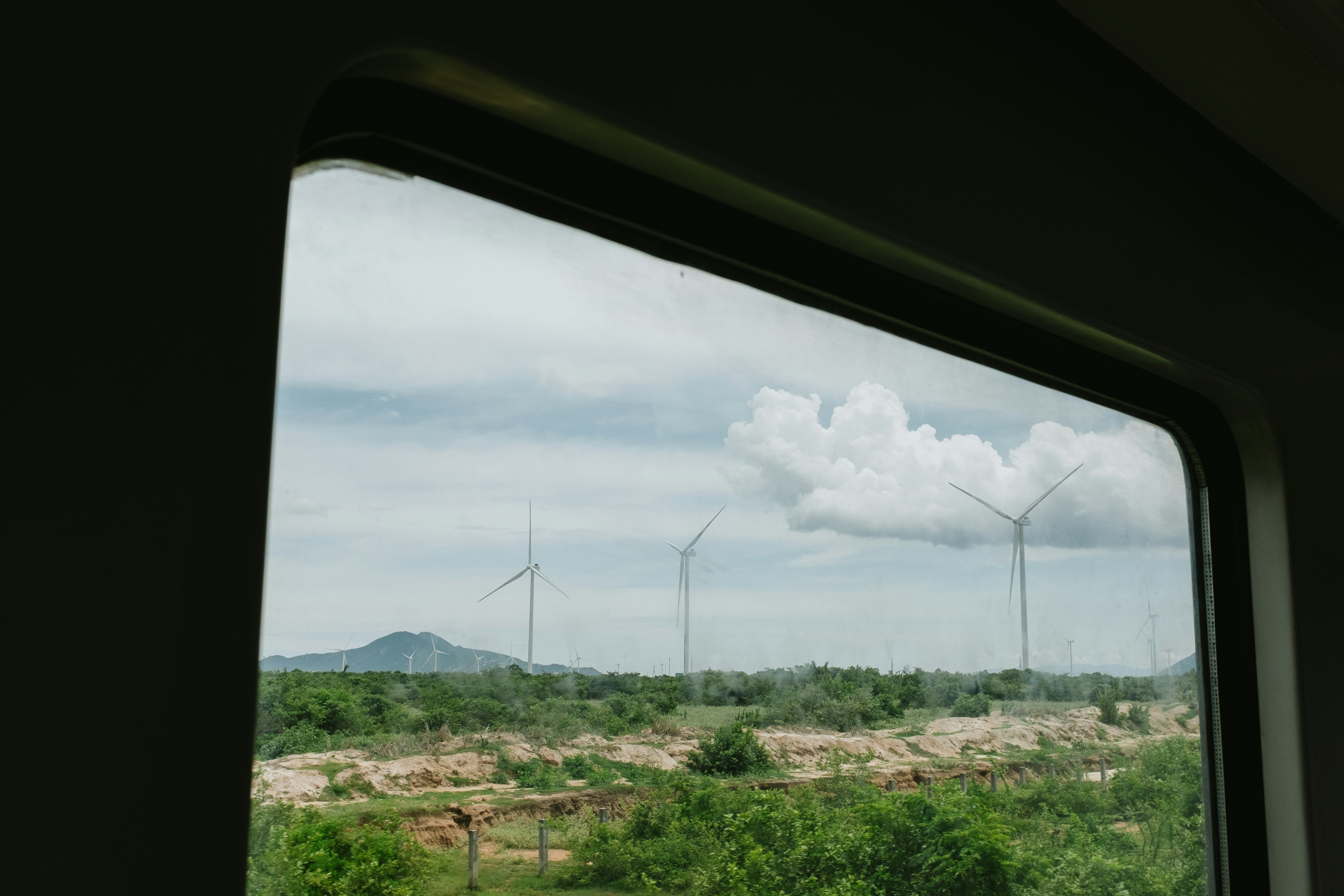 Wind turbines in a rural landscape under cloudy sky.