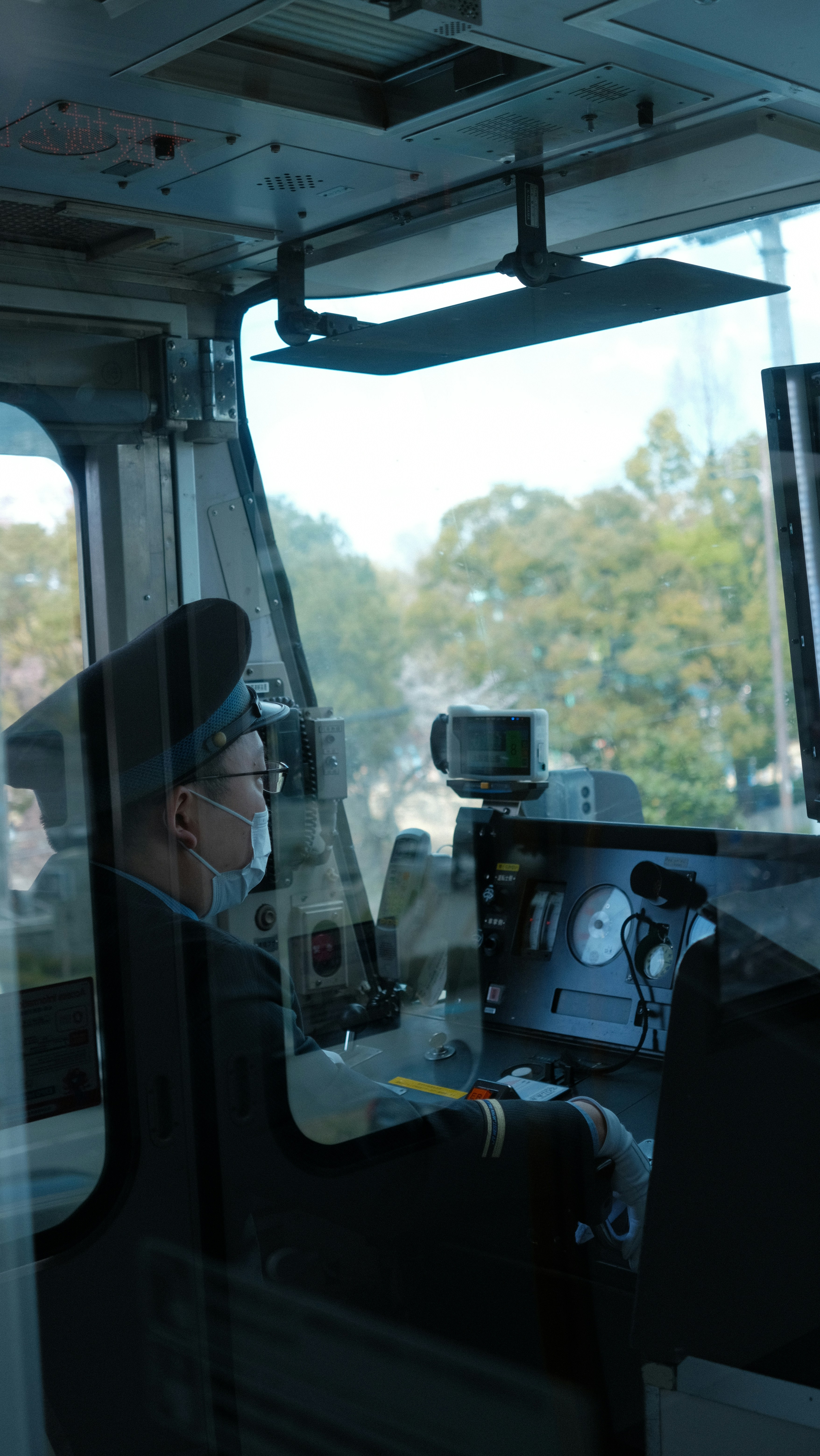 Train driver in uniform wearing a mask in the cabin.