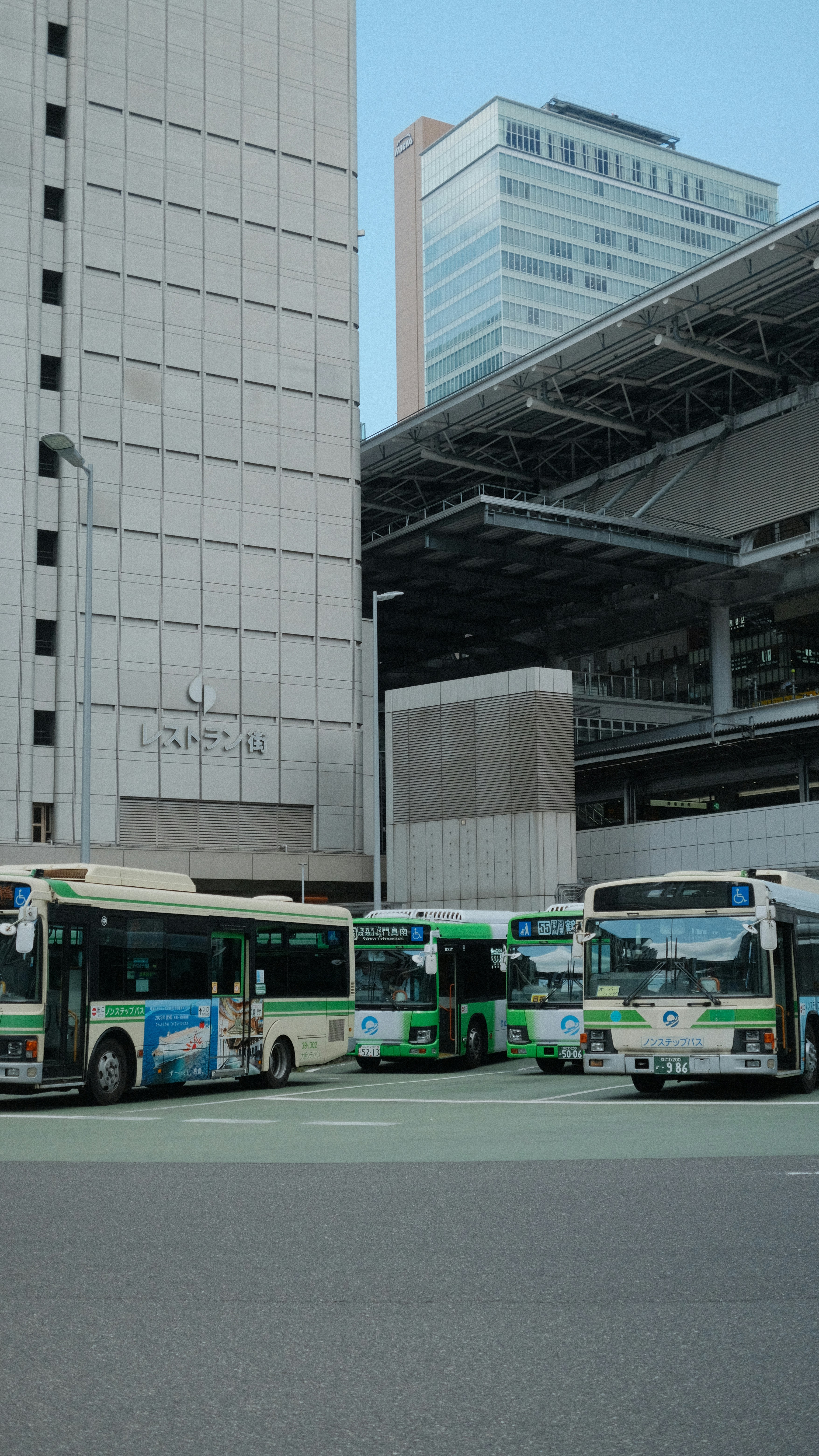 Several buses parked in front of modern buildings.