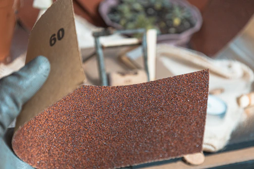 Hand holding sandpaper with grit number 60
