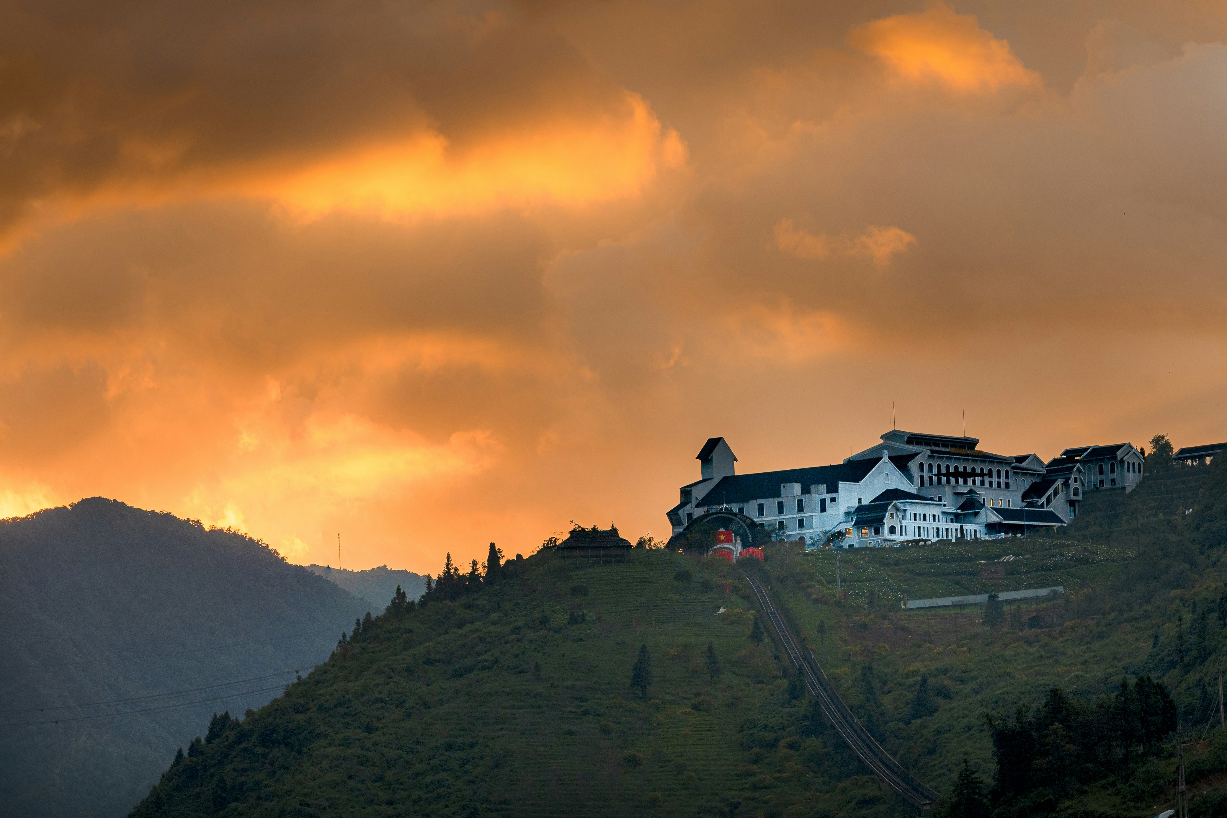 Building on a misty mountain under orange sky