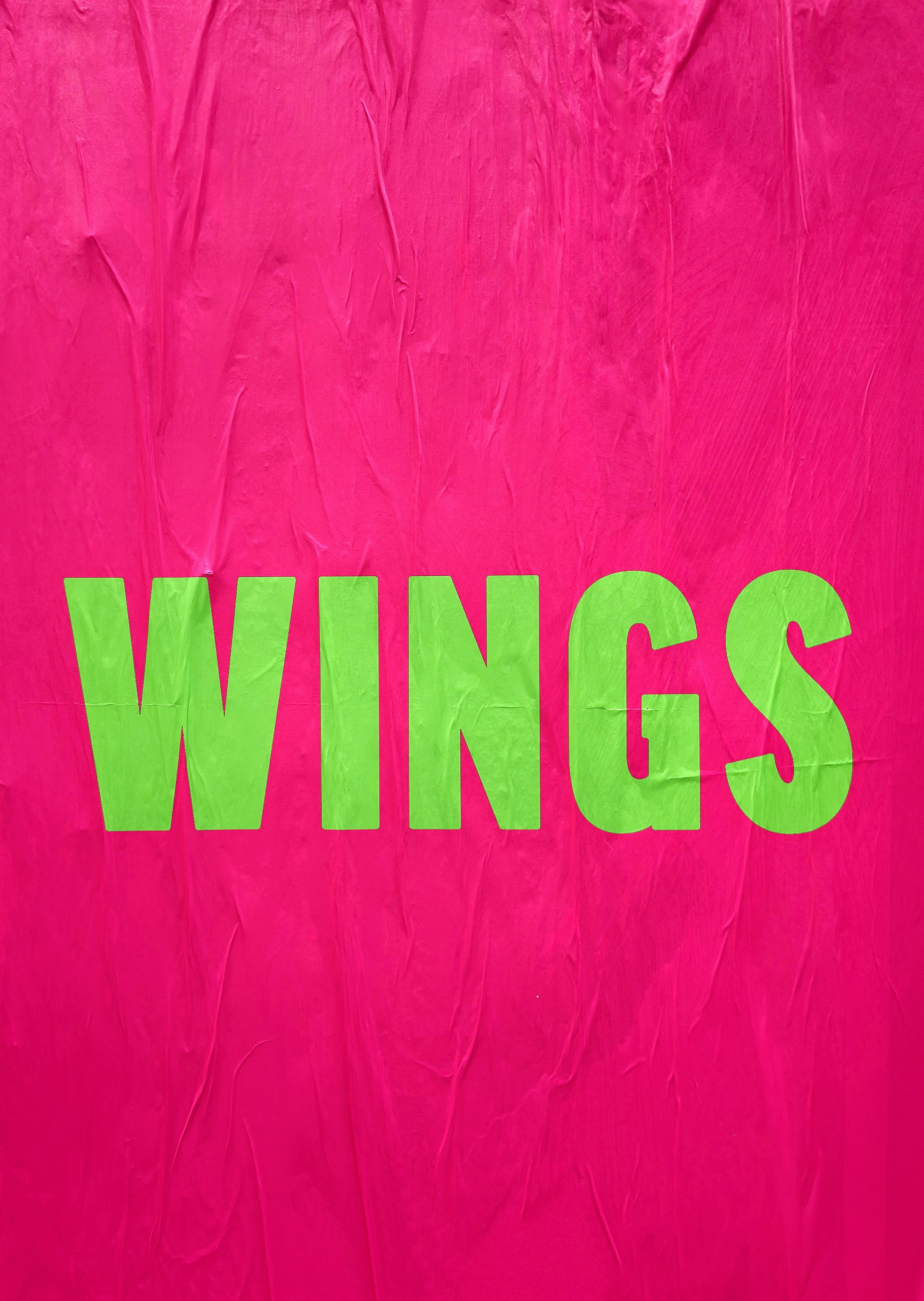 Green text spelling wings on pink background