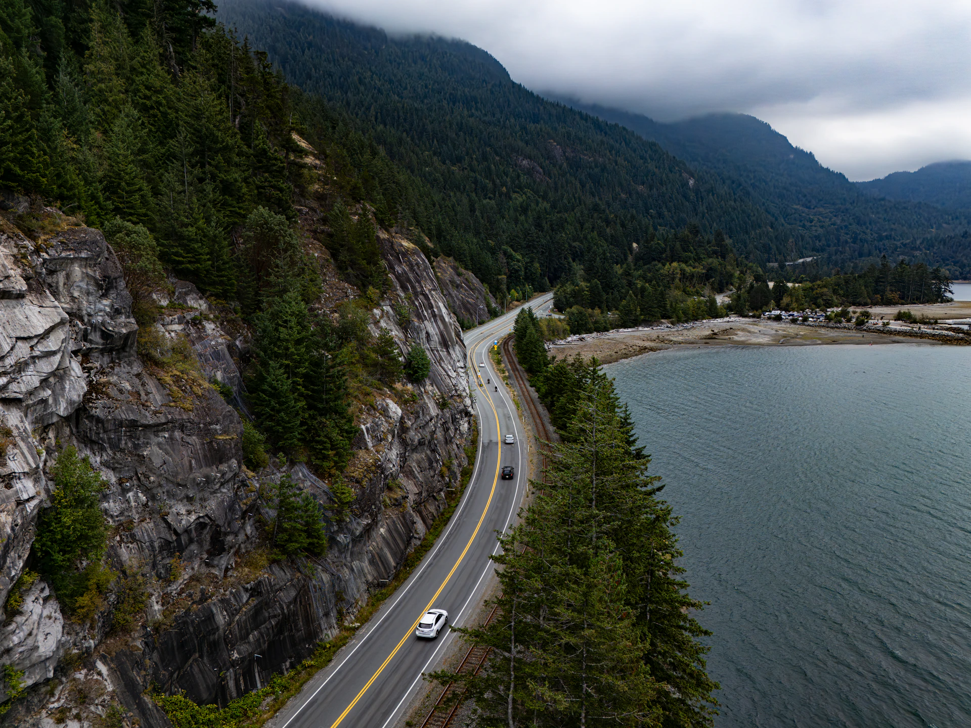 Coastal highway winding alongside a calm blue bay.