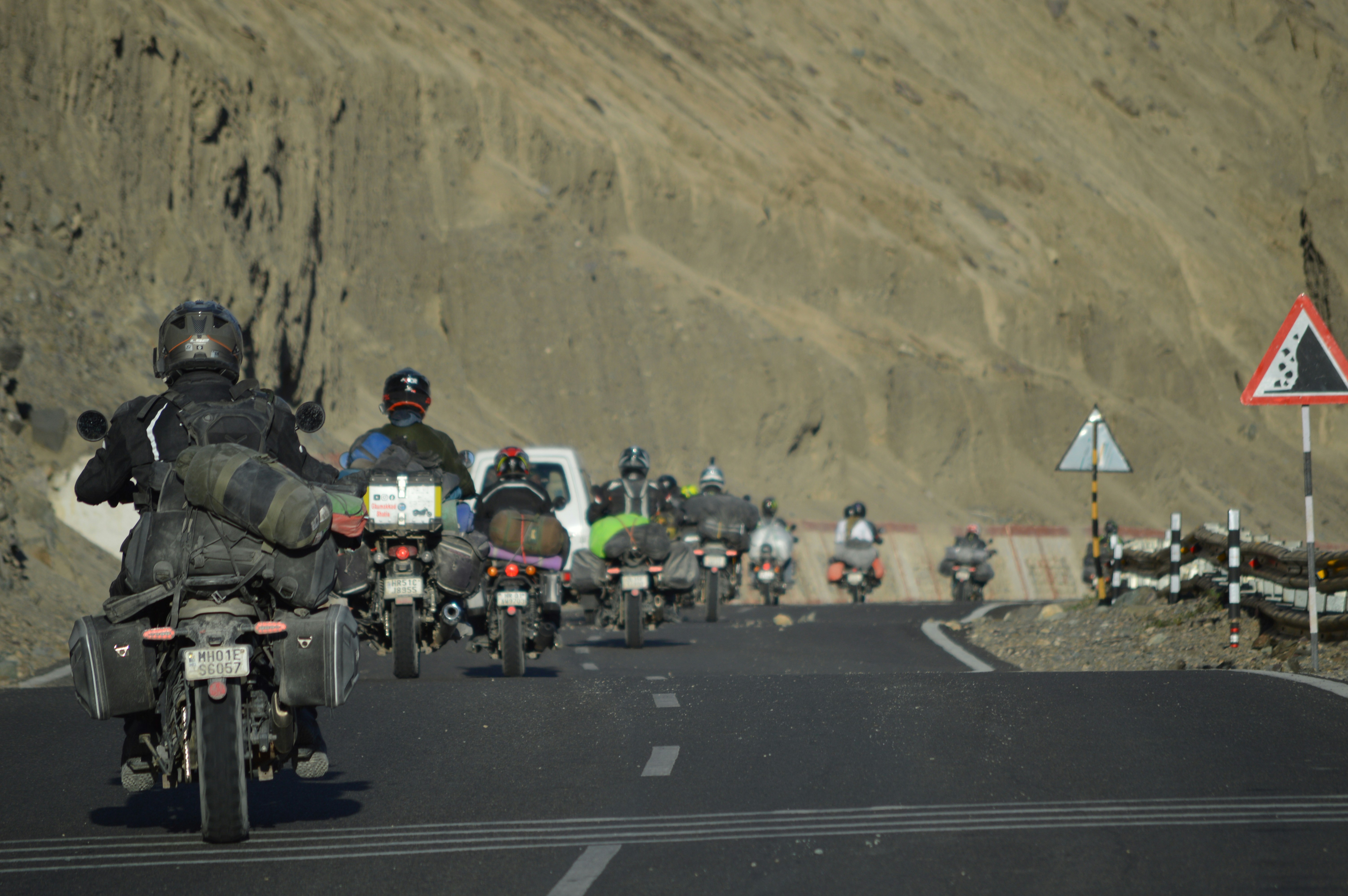 Motorcyclists travel on a mountain road with luggage.